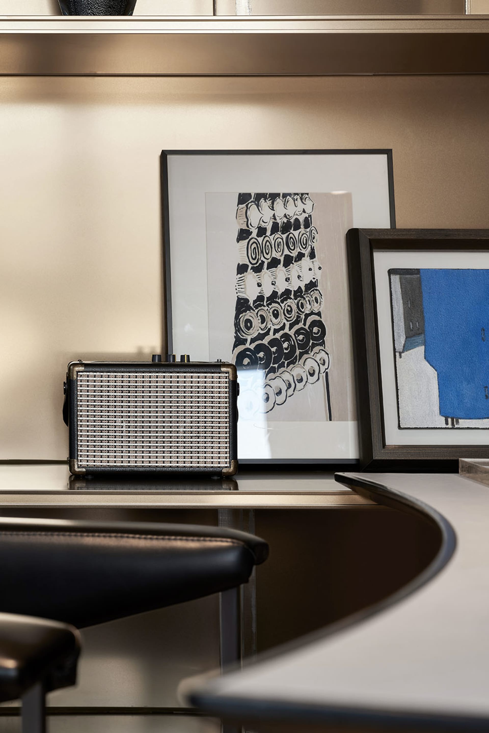 A modern office space featuring a metallic floating shelf and a sleek, curved concrete counter.