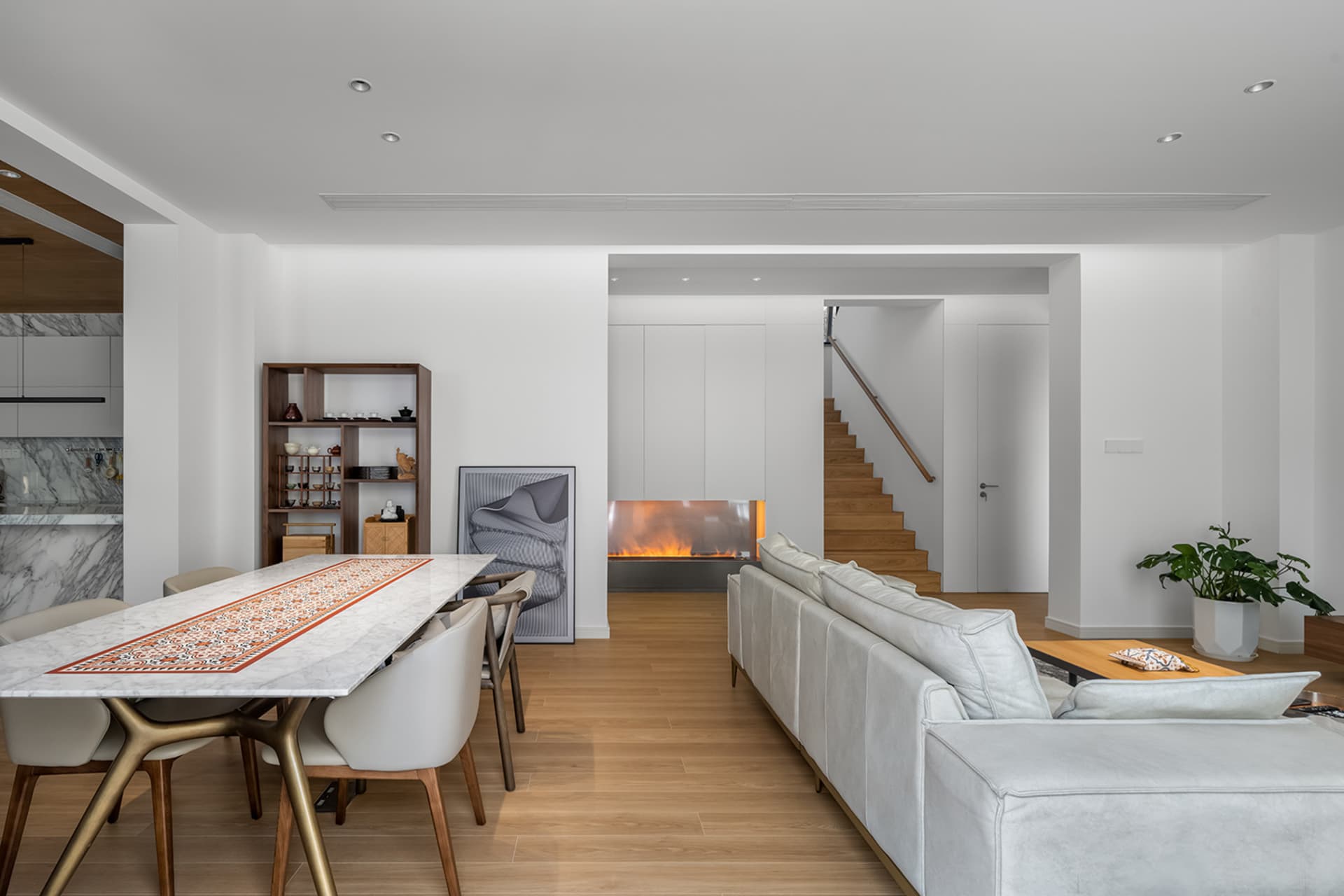 Modern dining room with white marble table and chairs, featuring a cozy fireplace and sleek white couch, surrounded by minima