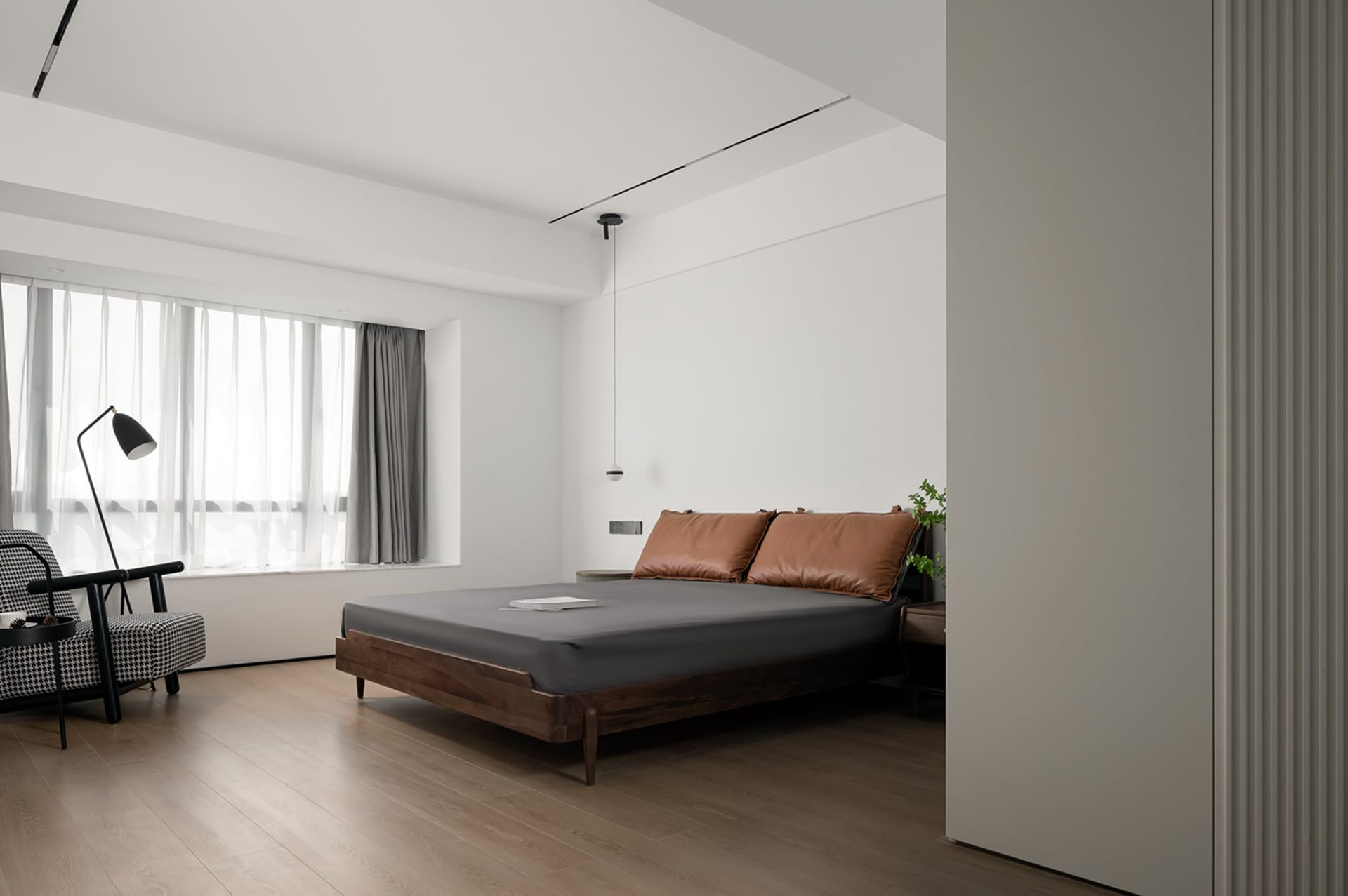 A minimalist bedroom featuring a wooden bed frame, leather headboard, and glass window with sheer curtains.