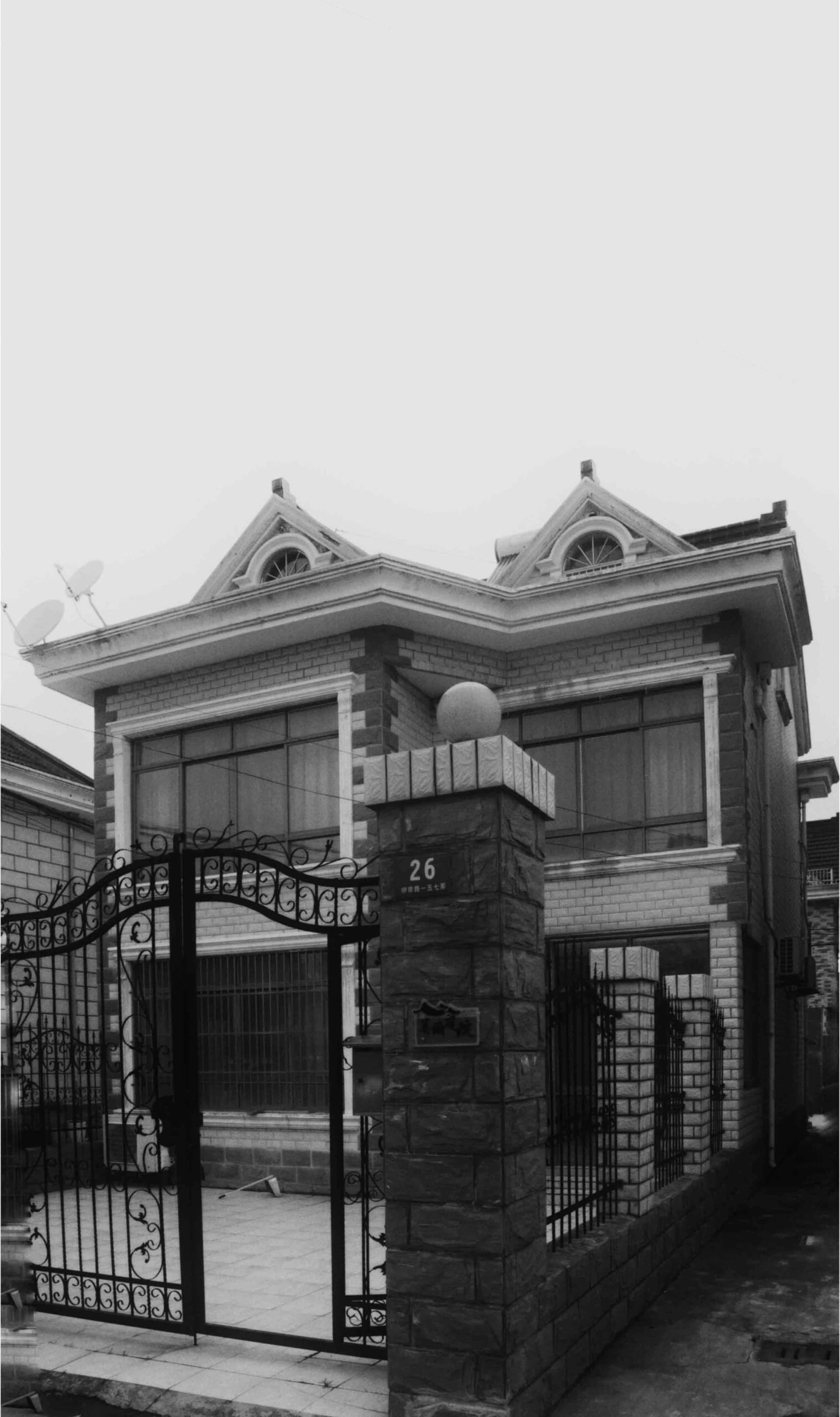 一棟現代住宅，外牆採用磚塊與混凝土材質，具雙層樓設計並設有大門入口。