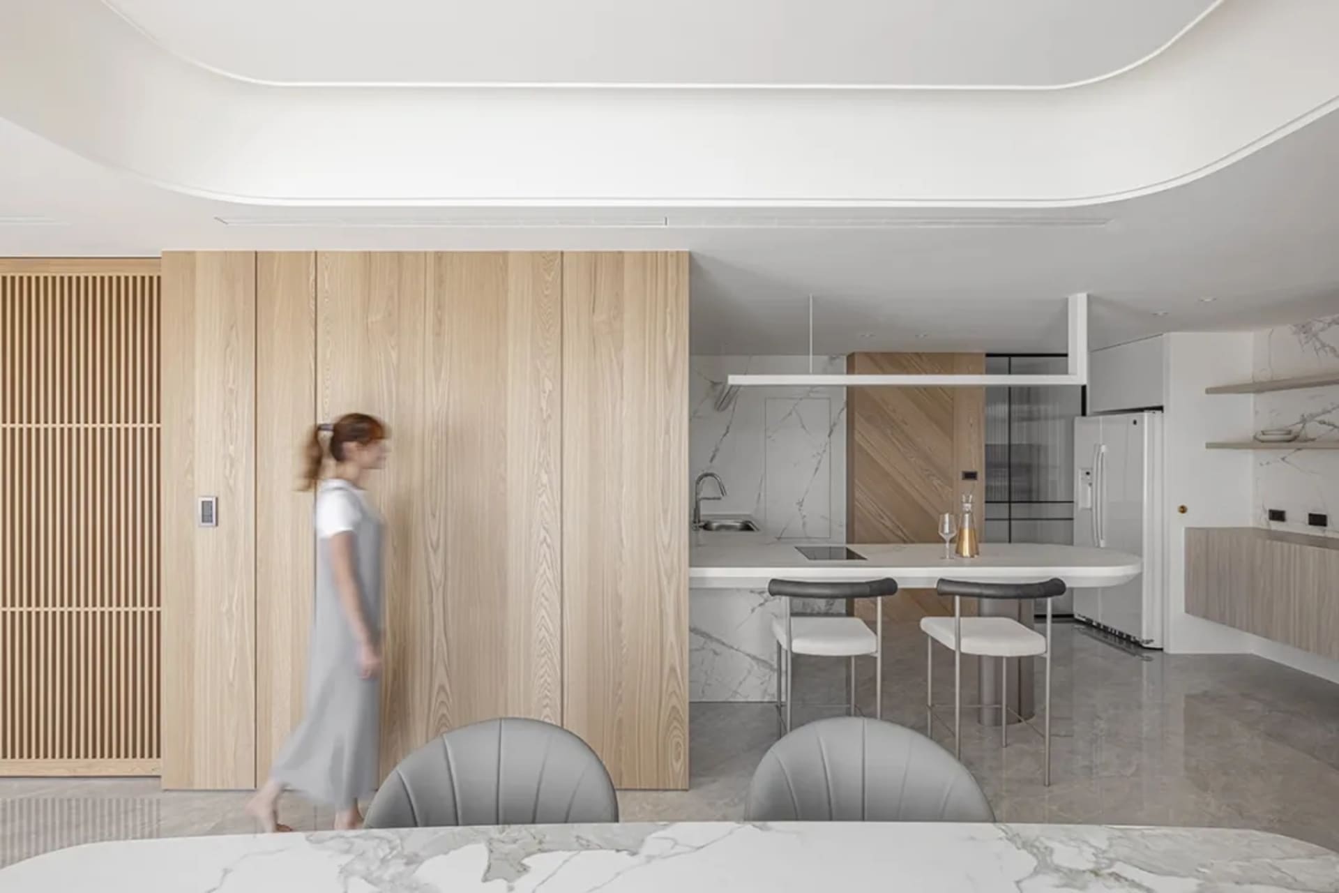 A modern kitchen with marble countertops, wood cabinetry, and stainless steel appliances.