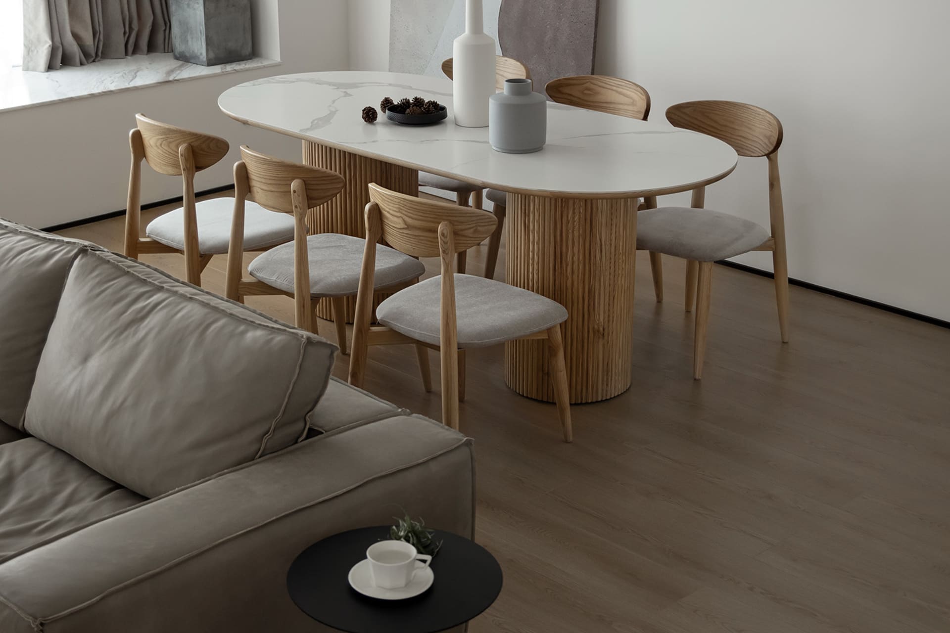 A modern minimalist living room featuring a wooden dining table with a marble top, upholstered furniture, and a mix of wood a