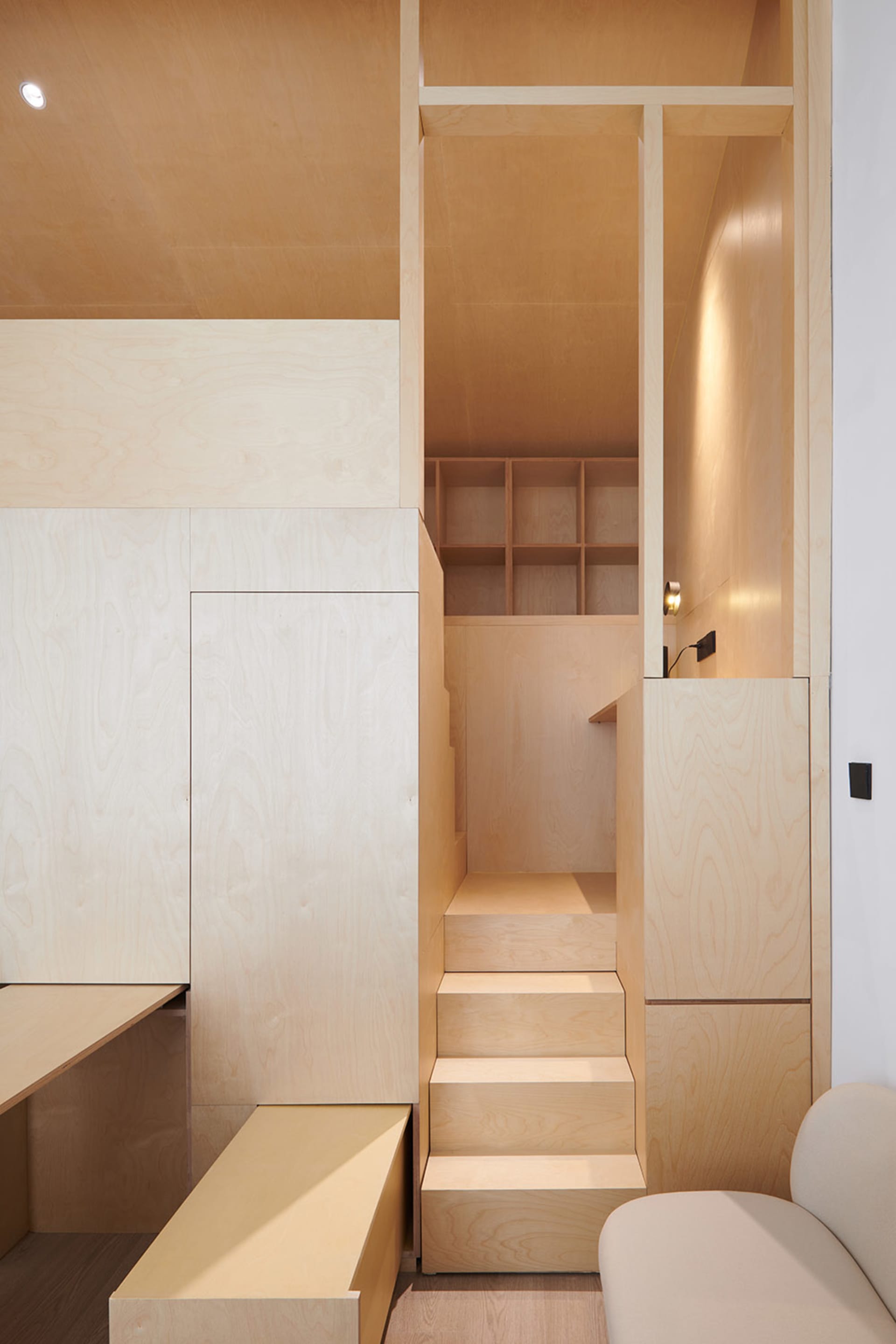 A minimalist residential interior with wooden stairs and storage units.