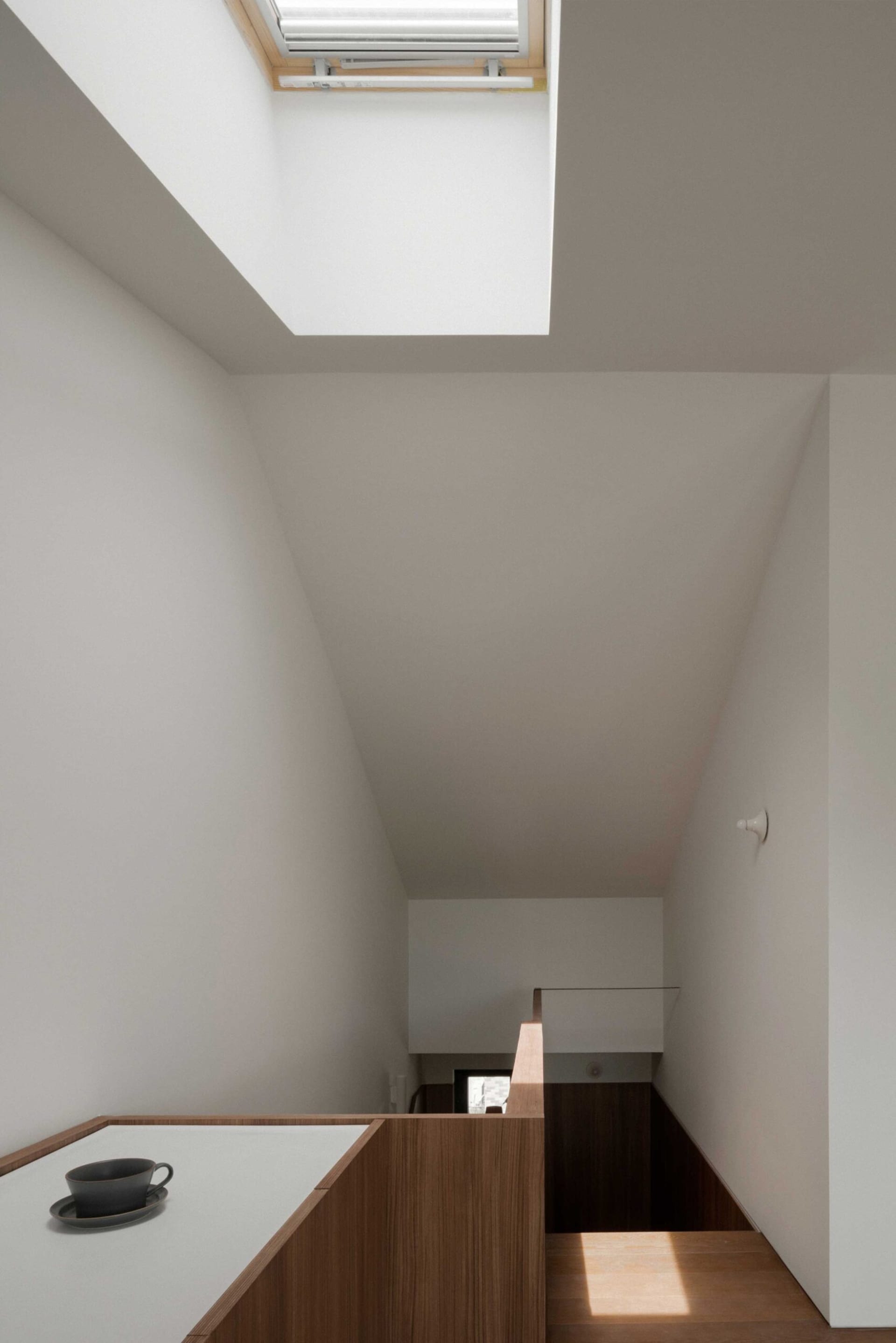 Modern residential staircase with wooden steps and a skylight above.