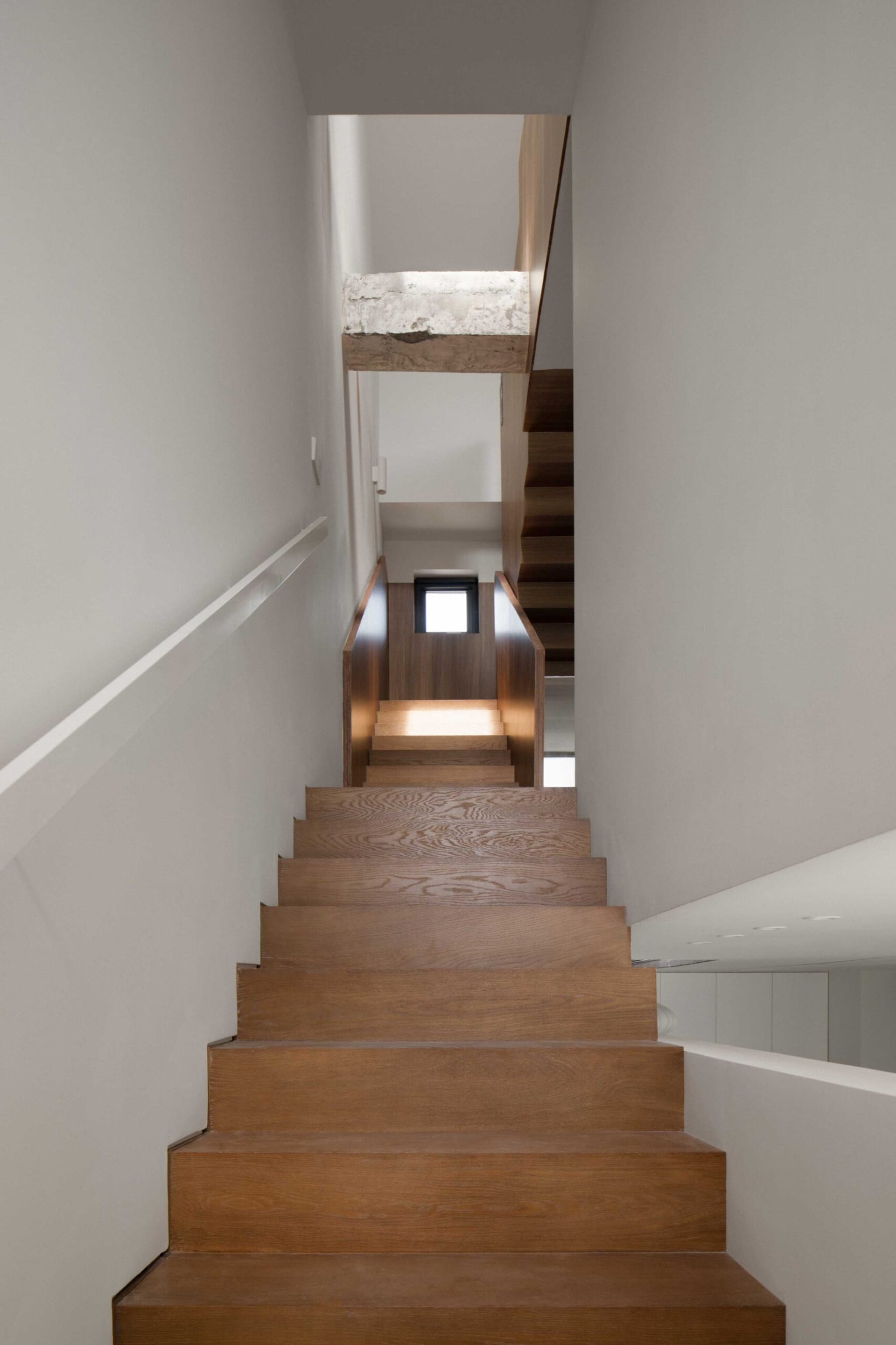 A modern wooden staircase interior with a minimalist design and white walls.