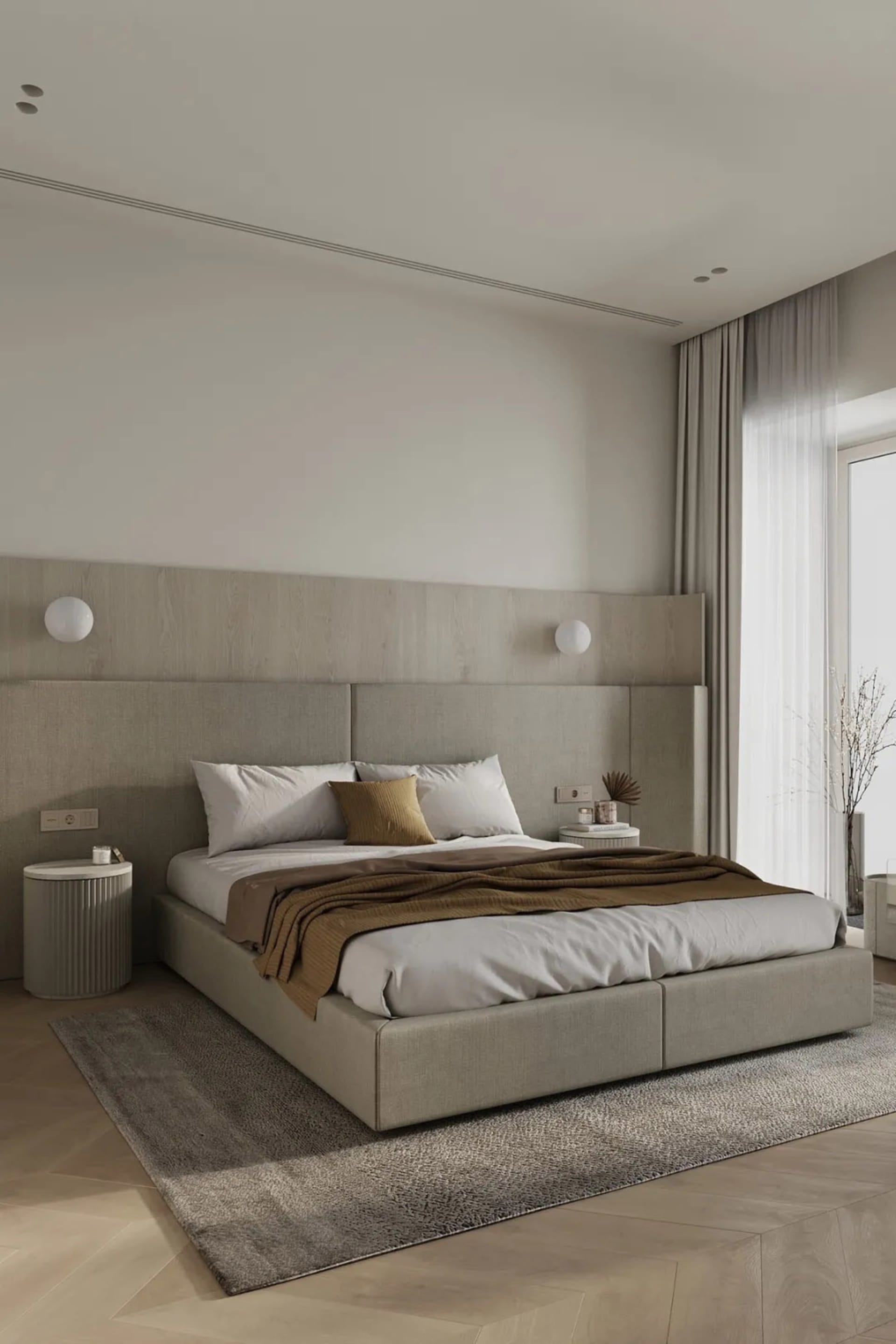 A minimalist bedroom with a fabric upholstered bed, white walls, and a large window with light-colored curtains.