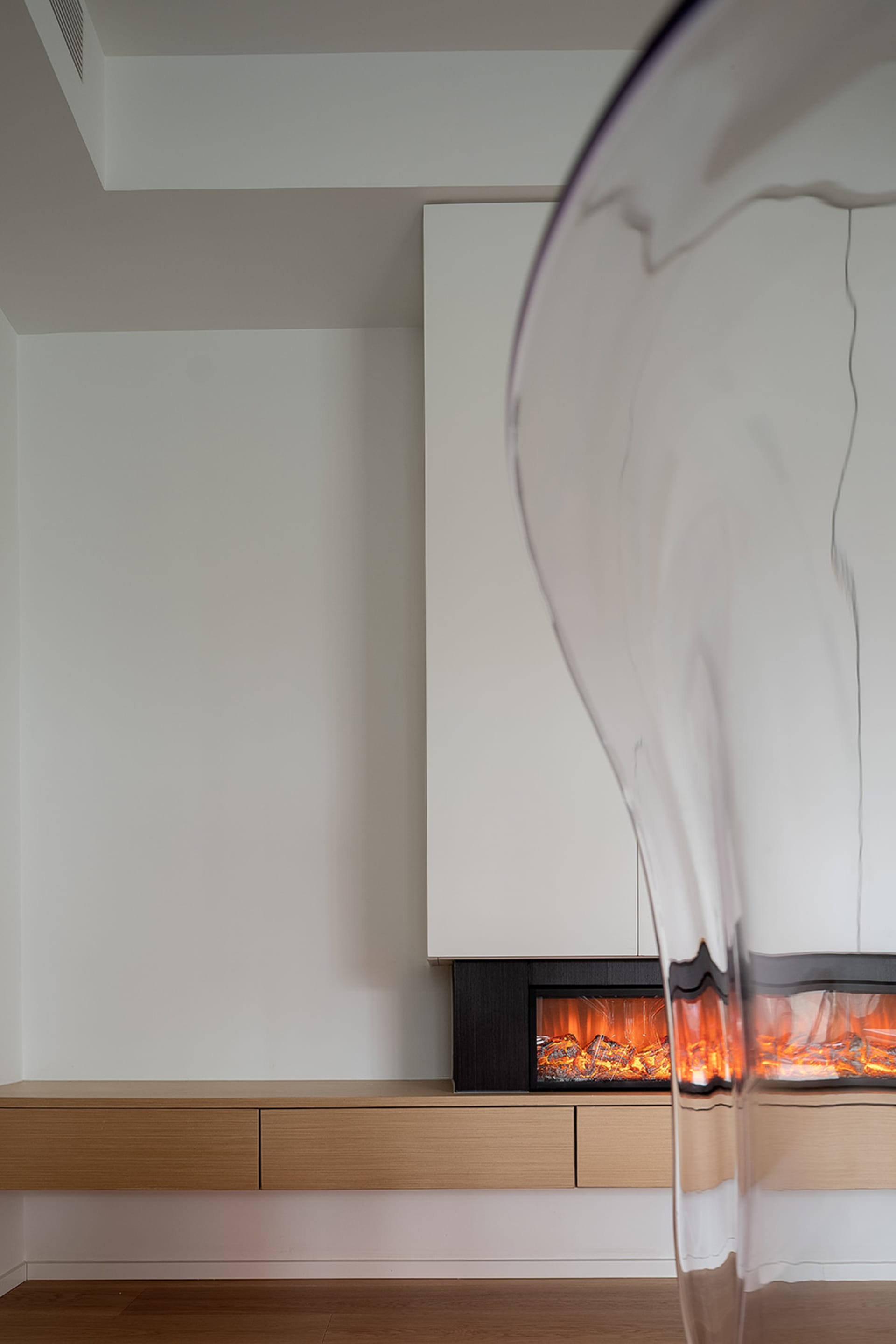 A minimalist living room featuring wooden furniture and a fireplace.