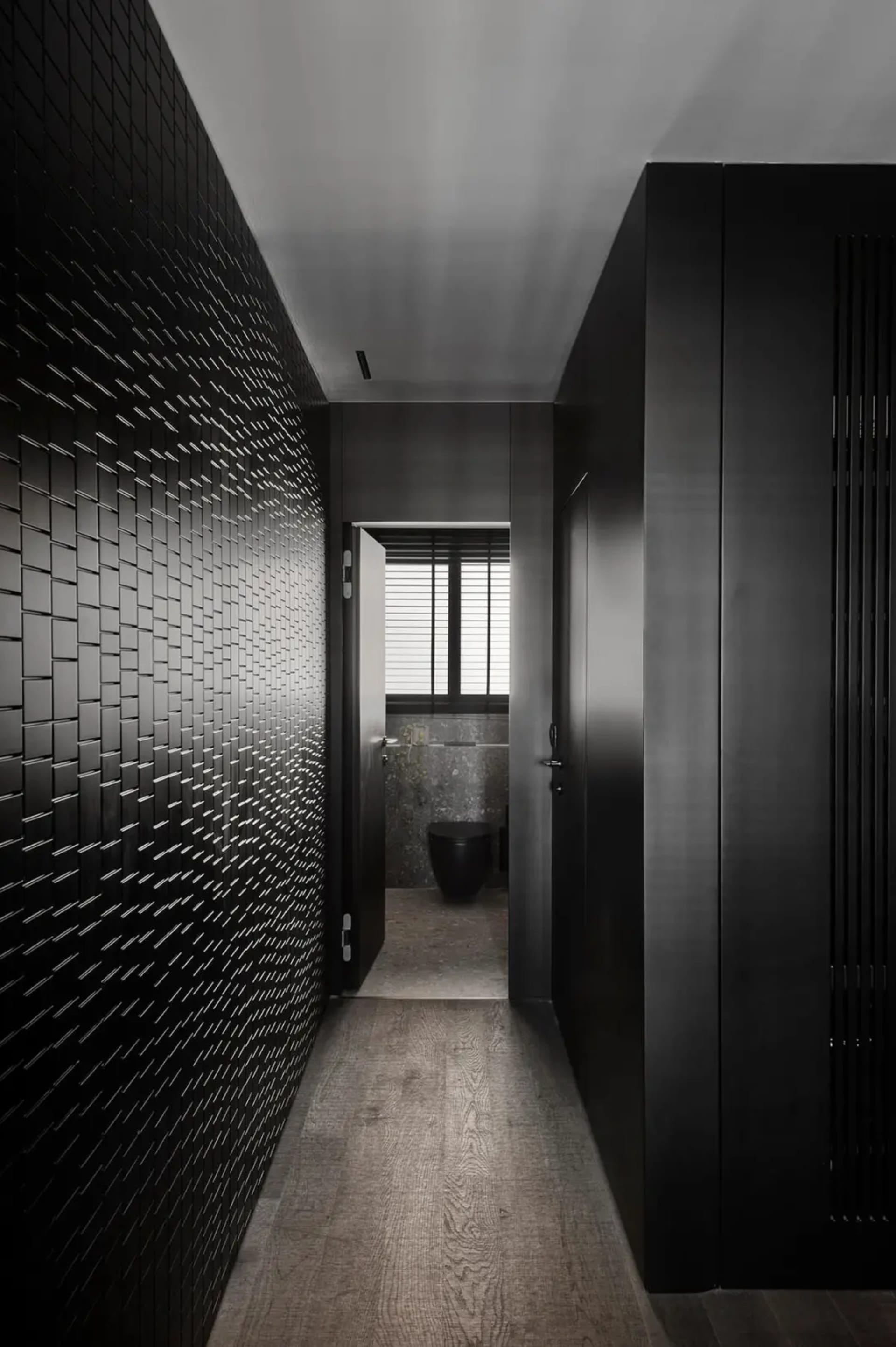 Modern bathroom with black tiled wall and wooden floor