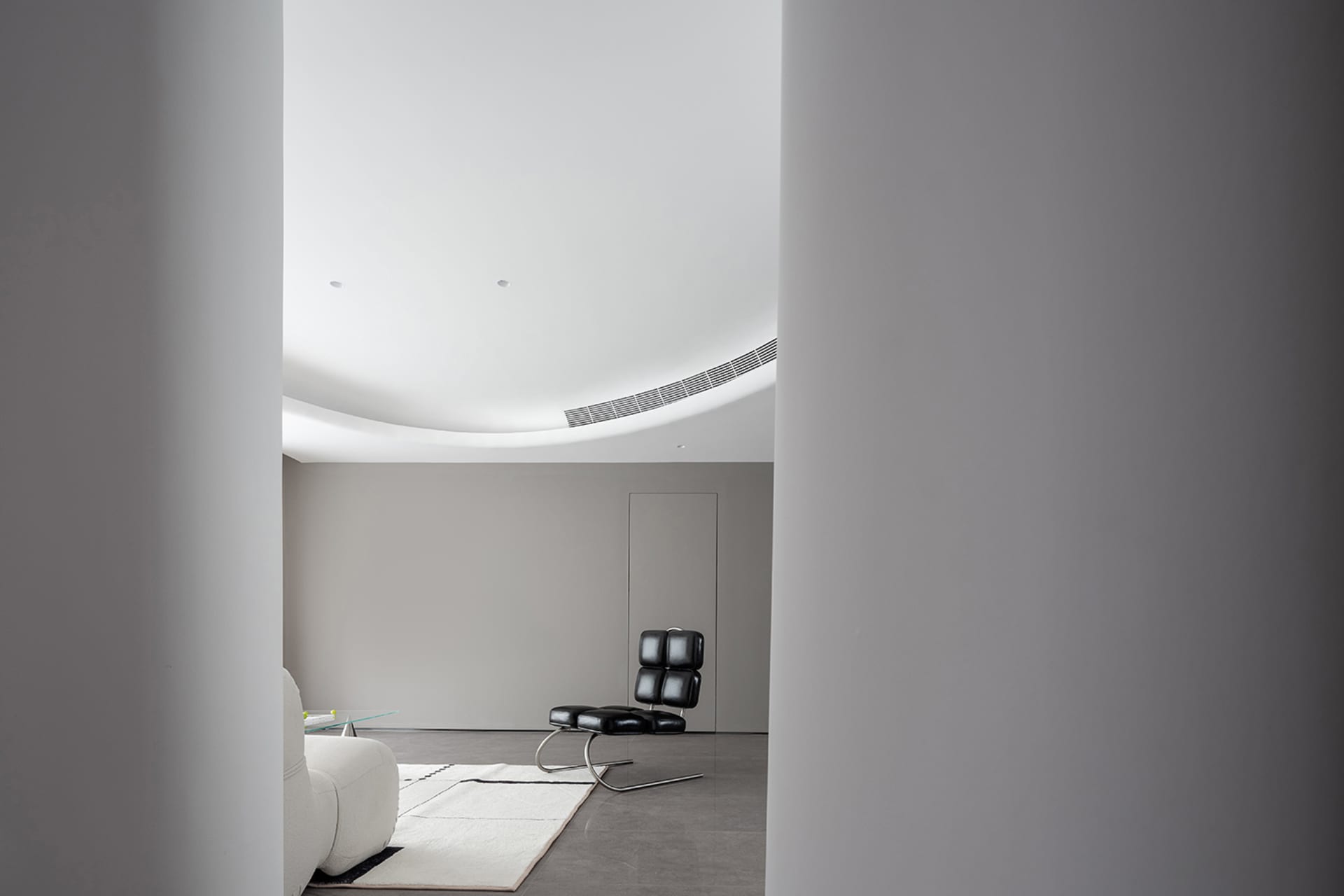 A modern living room featuring minimalist furniture and a concrete floor.