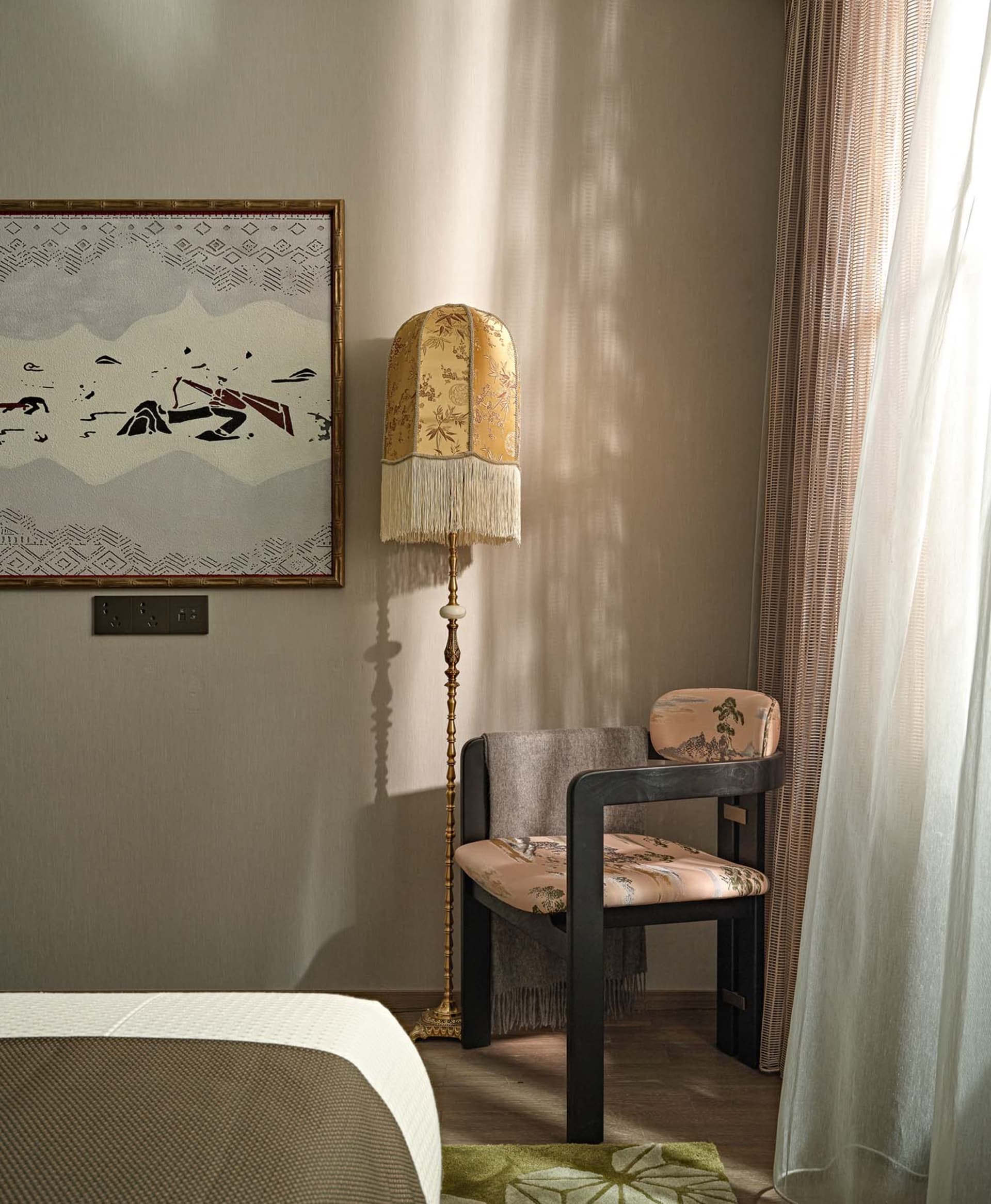Modern living room showcasing a comfortable chair with patterned cloth upholstery and a decorative floor lamp with a floral-p