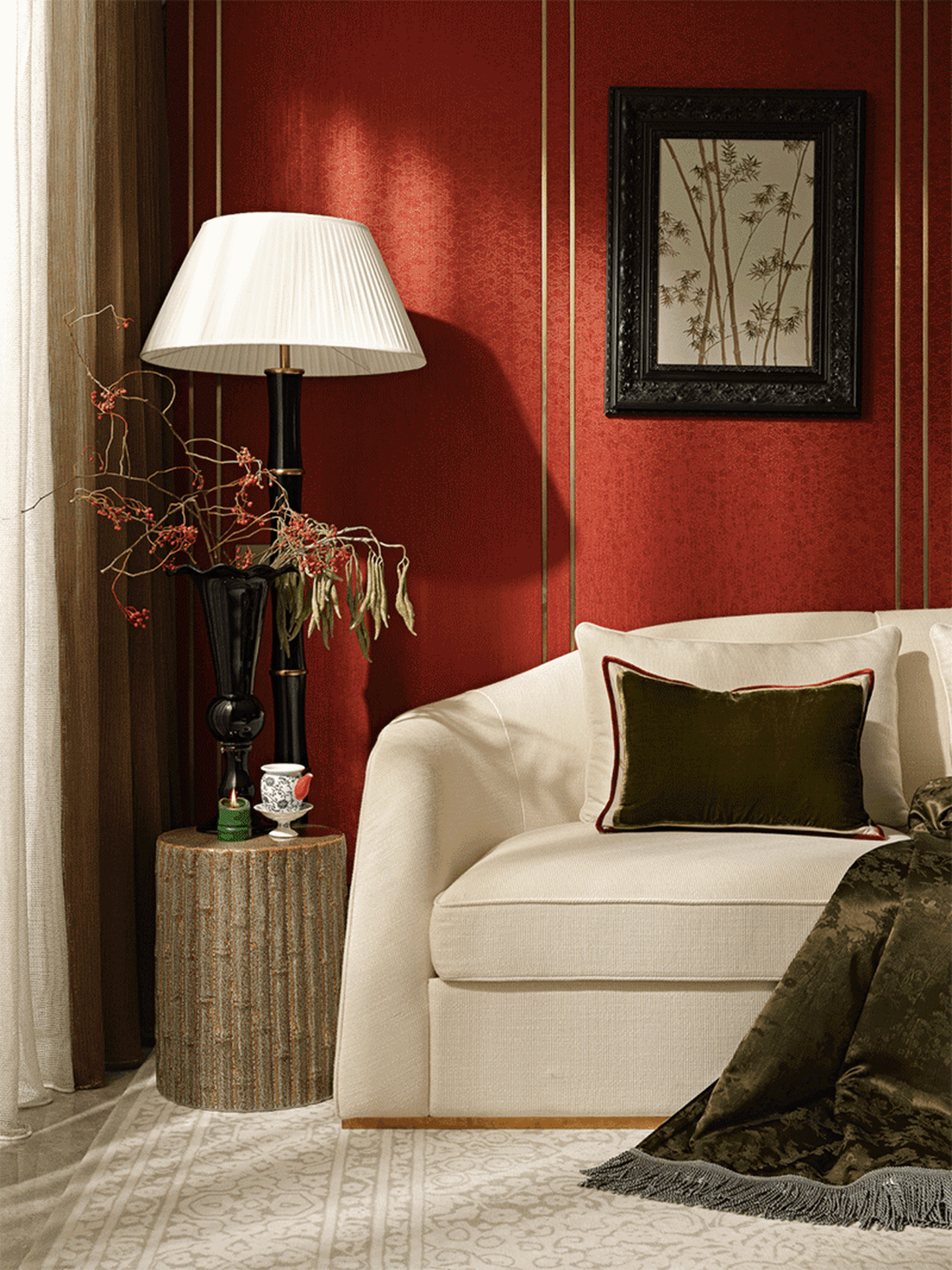 A modern living room with a white sofa placed against a red textured wall, featuring a lamp, a small wooden table, and a blac