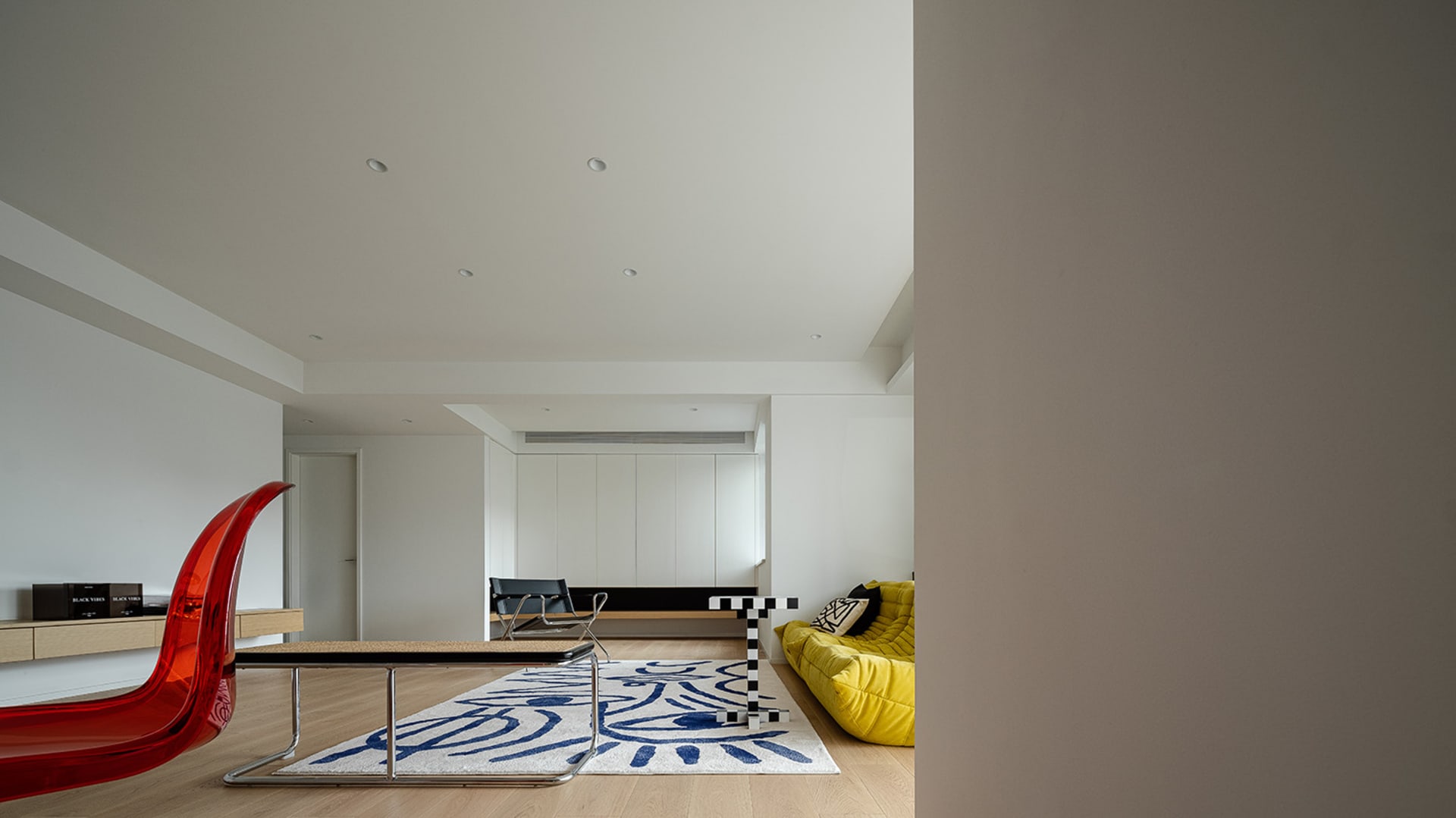 Modern living room featuring a contemporary wooden floor, glass windows, and upholstered furniture with a colorful rug.