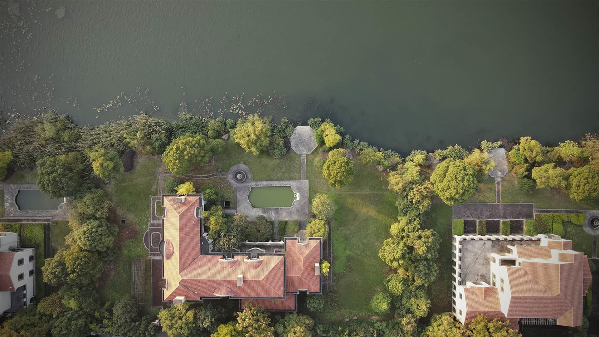 A modern residential property with a brick roof overlooking a large body of water.