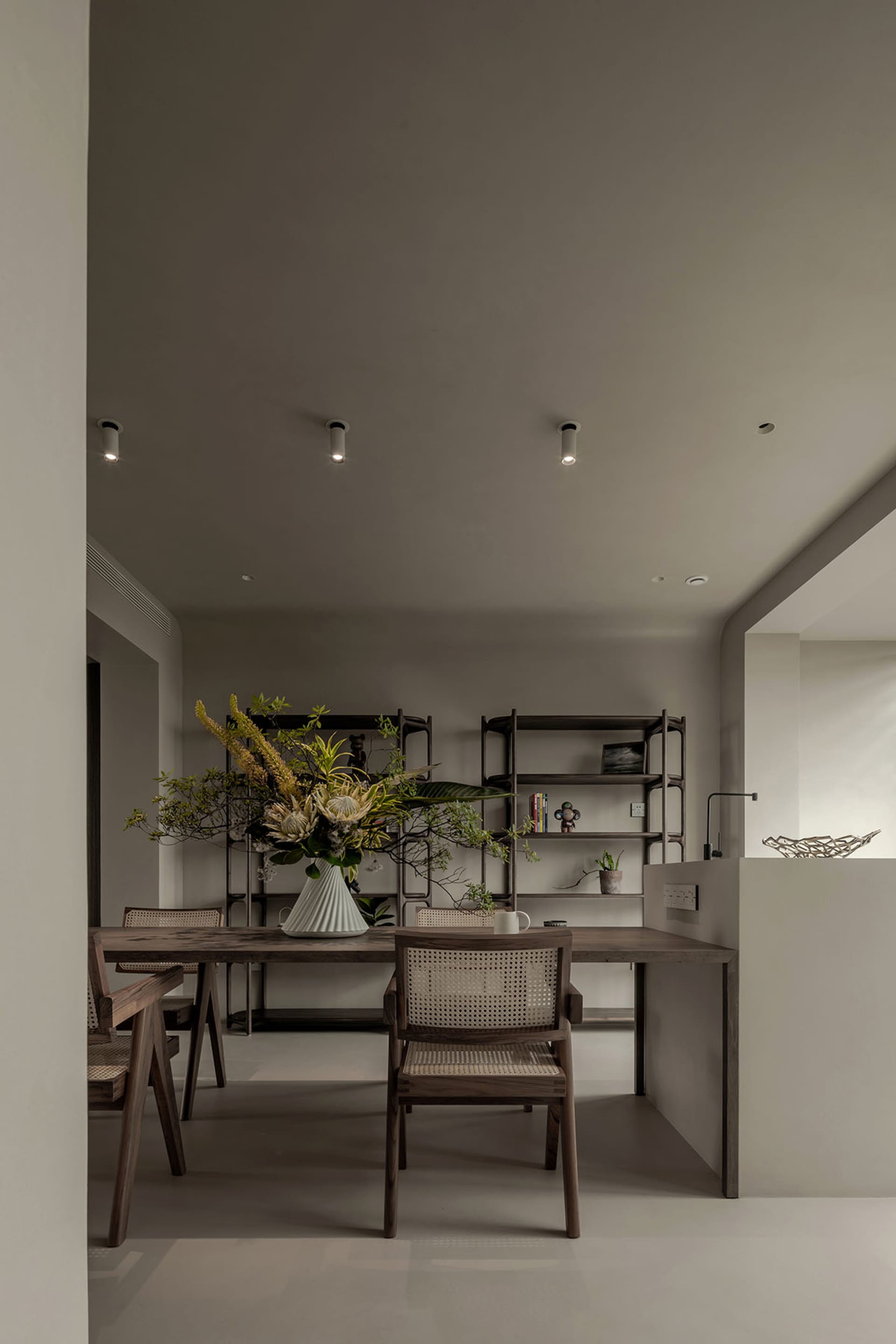 A modern, minimalist home office featuring wood furniture and a vase with floral arrangement.