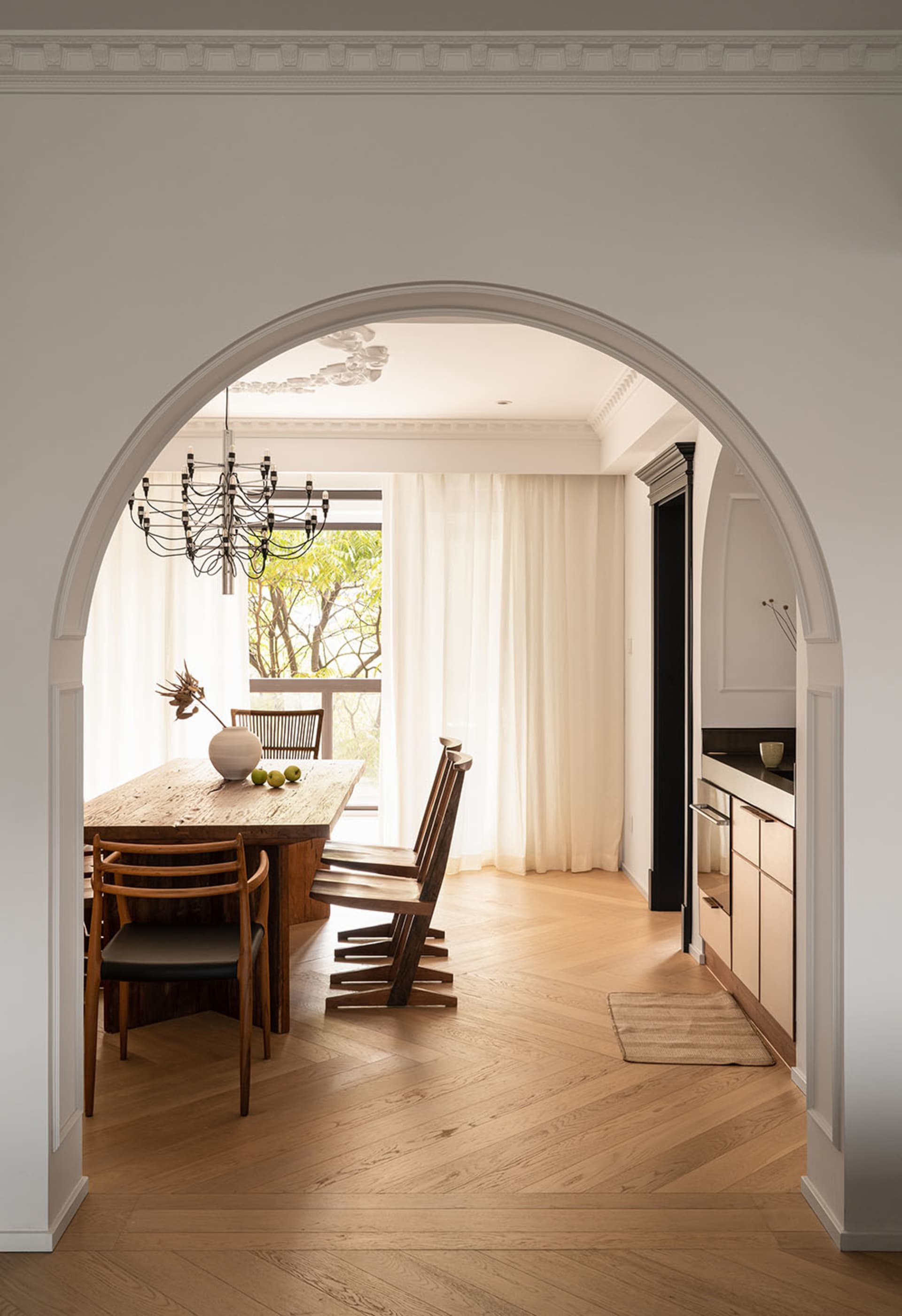 Modern dining room featuring wooden furniture, a chandelier, and a view of an outdoor balcony.