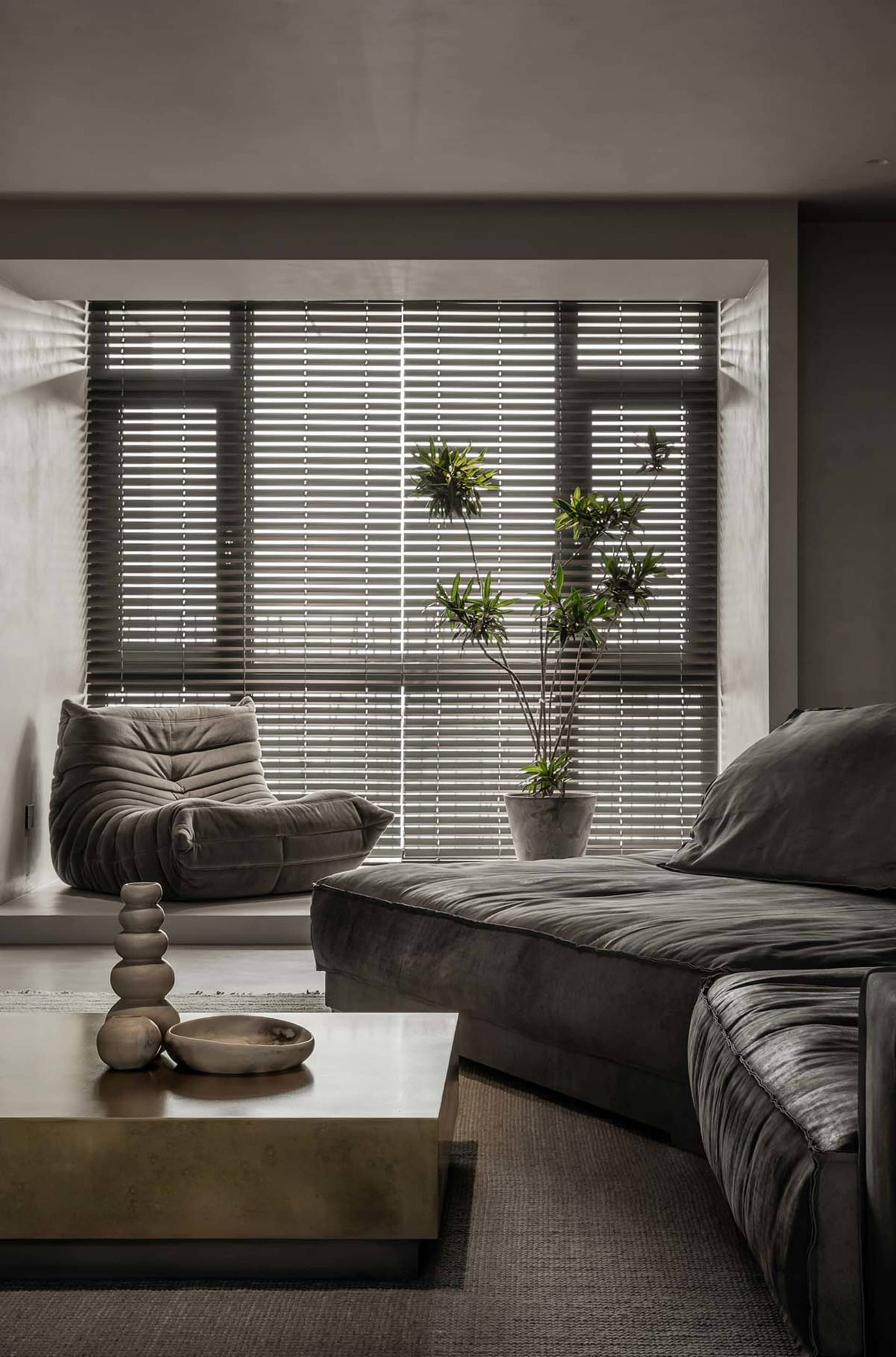 Modern minimalist living room featuring a plush velvet couch, a sleek concrete coffee table, and wooden accents on a polished