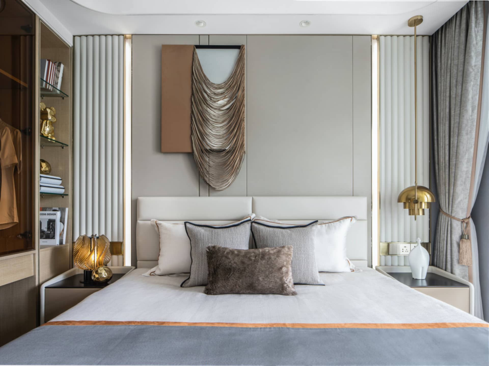 A modern minimalist bedroom featuring a bed with textured cloth, metallic pendant lights, and a gold-framed mirror.