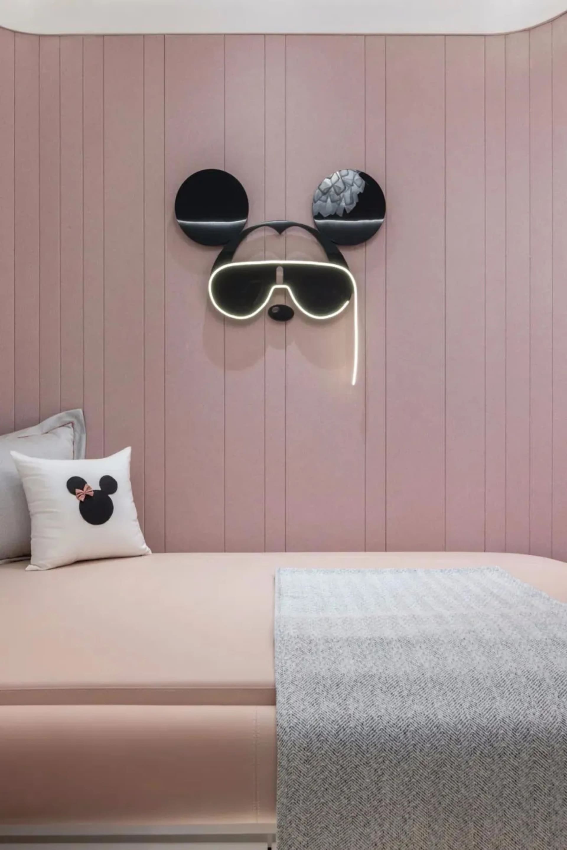 A minimalist bedroom with pink paneled walls and neon light