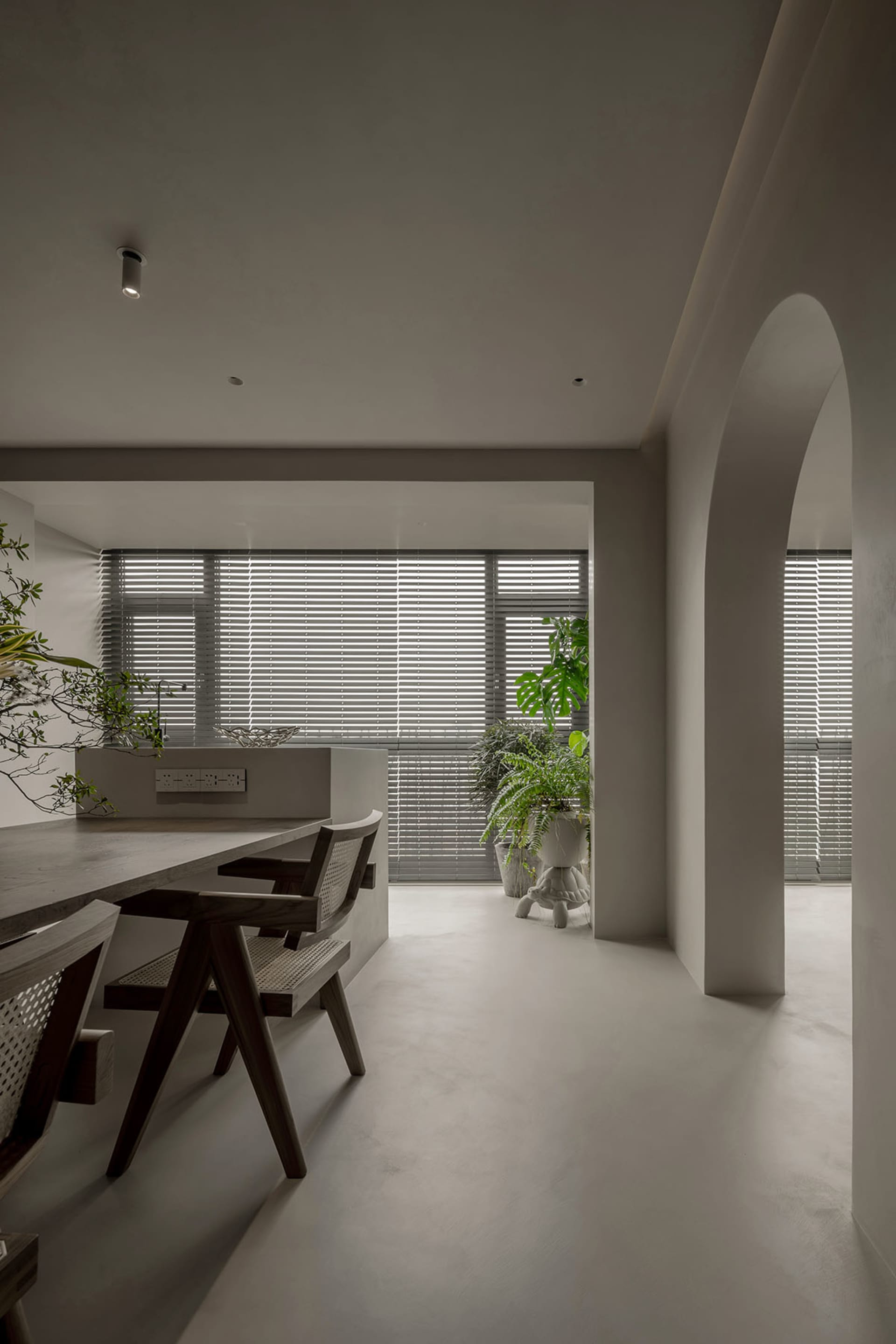 Minimalist residential dining area with concrete floor, wooden table, and chairs.