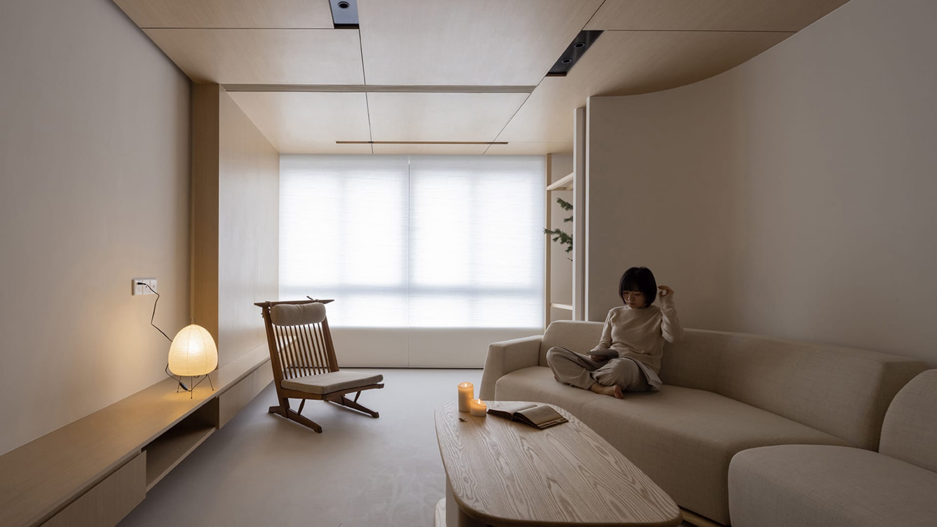 A modern minimalist living room with a white couch, wooden floor, and wooden coffee table.