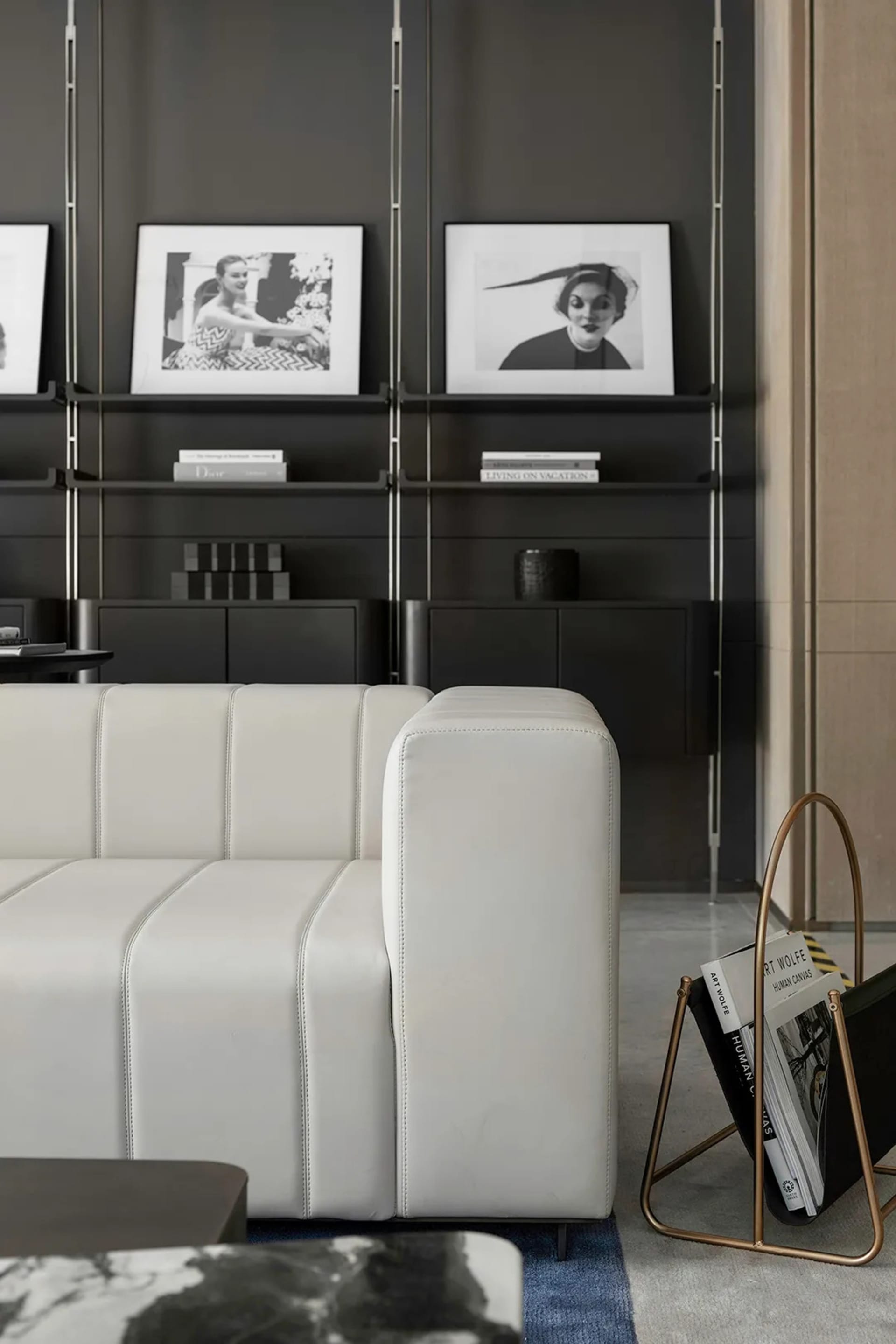 A modern industrial living room with a white leather couch, black shelves, and black and white wall art.