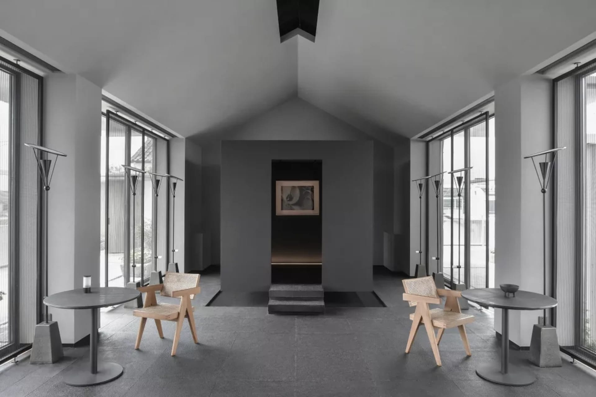 Modern industrial waiting area with concrete walls, wooden furniture, and vertical windows