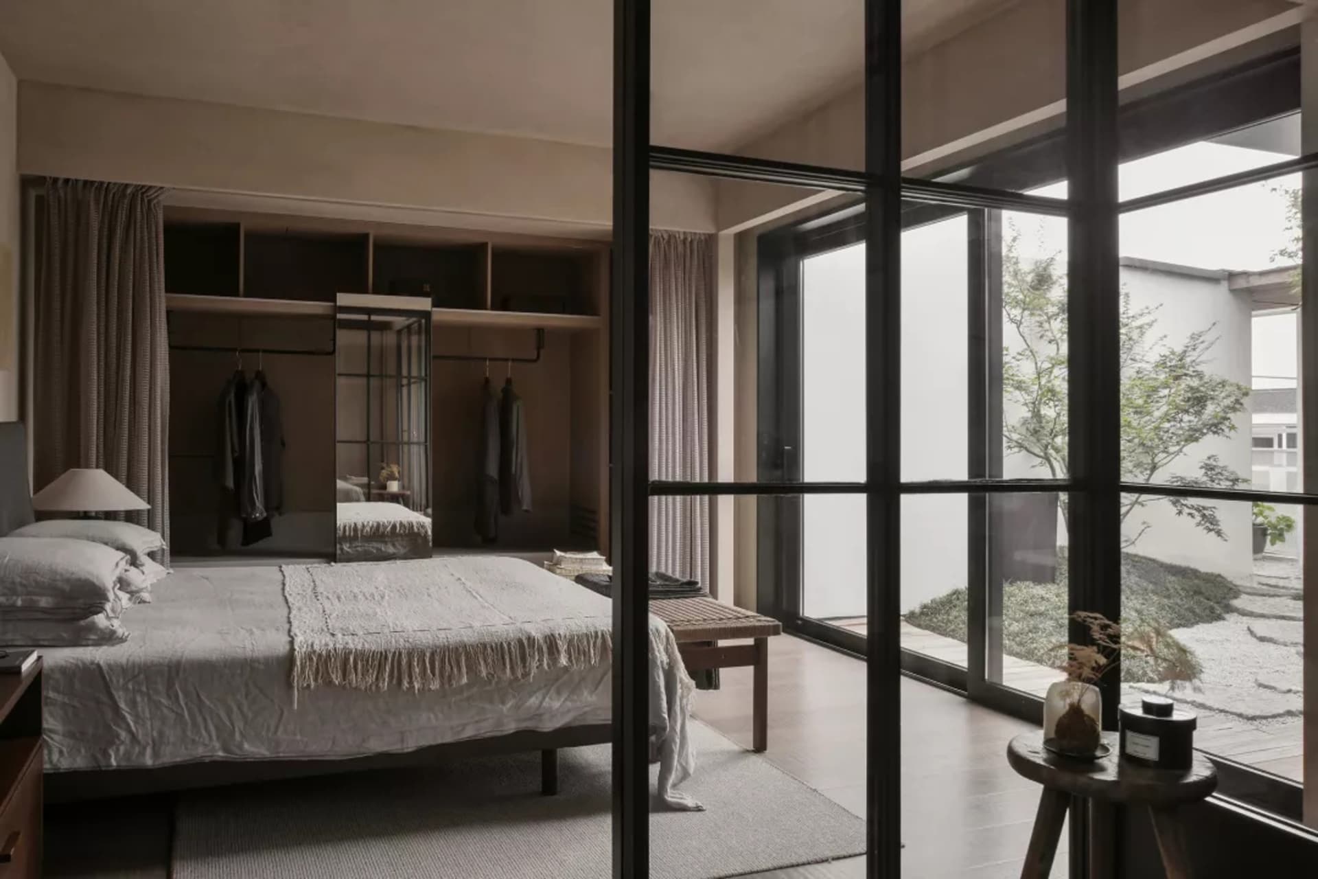 A minimalist bedroom with a wooden bed, white sheets, and a simple wooden side table.