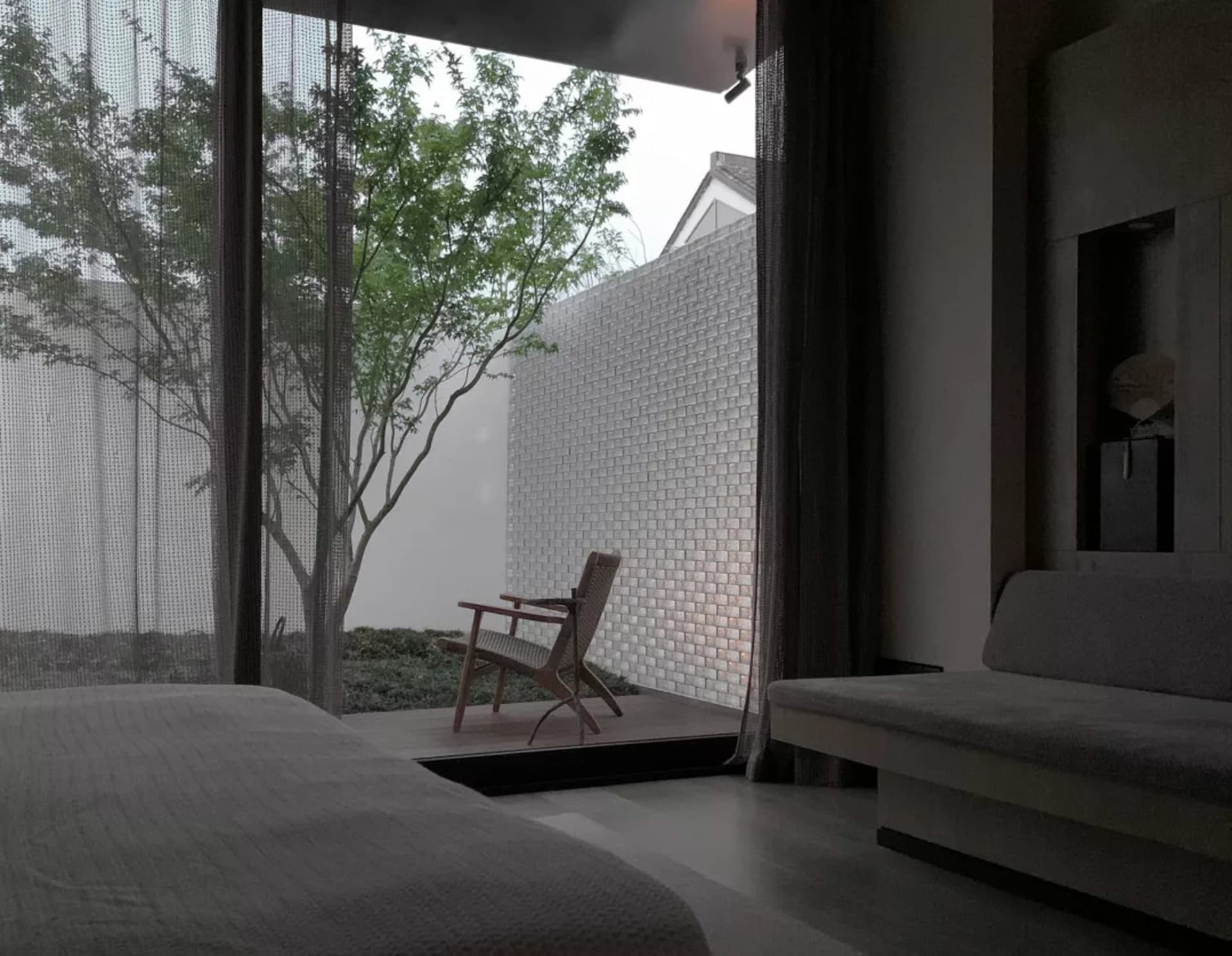 Living room with modern design, glass walls, wooden furniture, and brick elements.