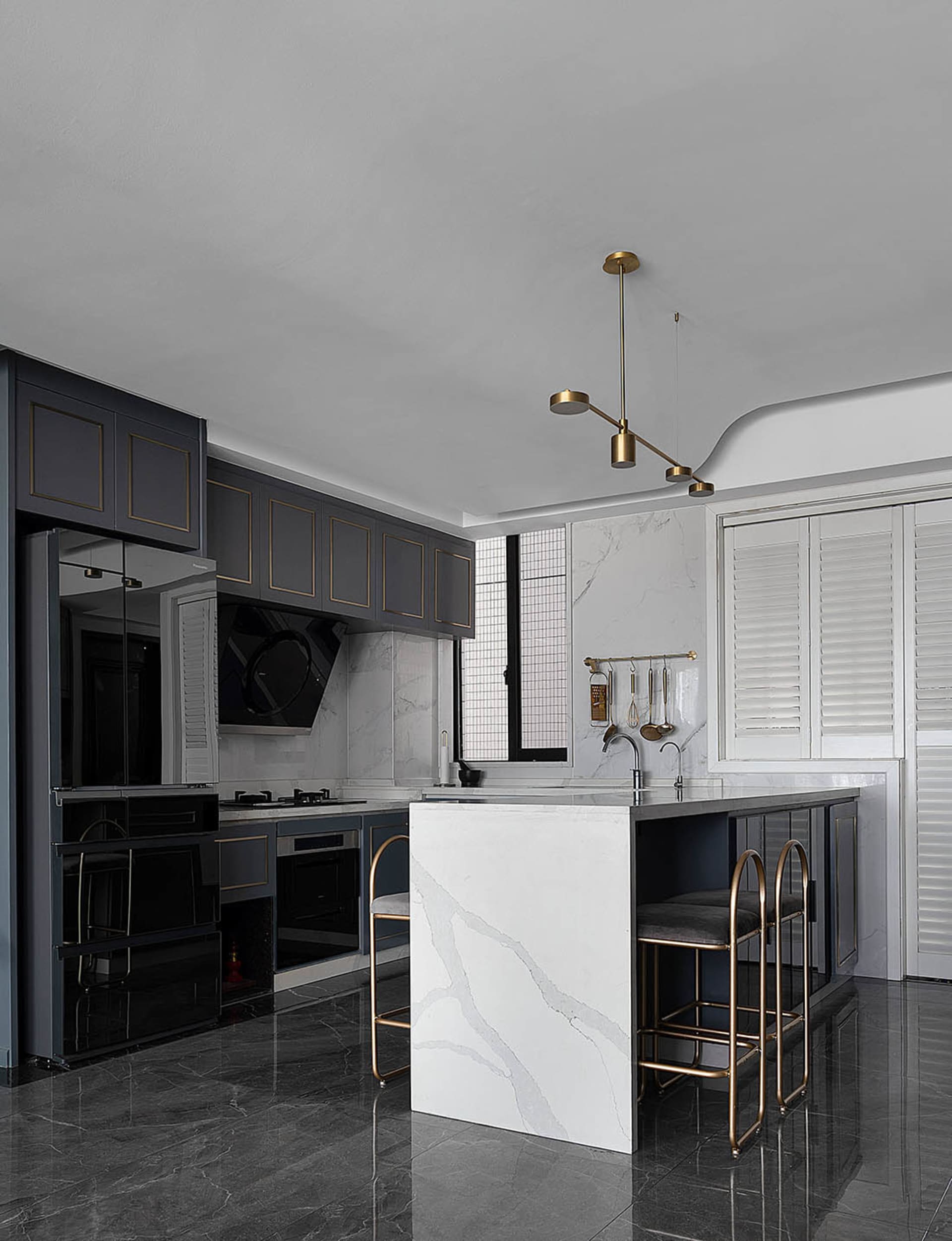 A modern minimalist residential kitchen with a white marble island and black cabinetry.
