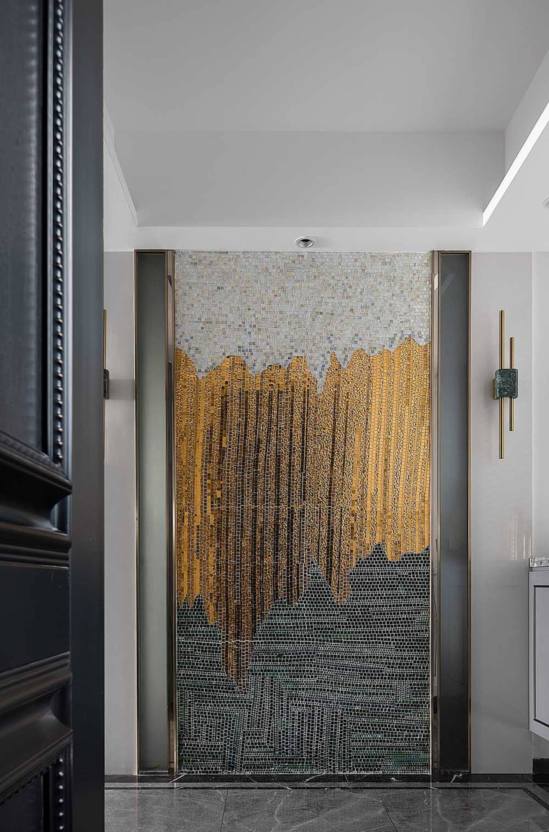 A modern interior design featuring a glass panel with intricate gold and black patterns.