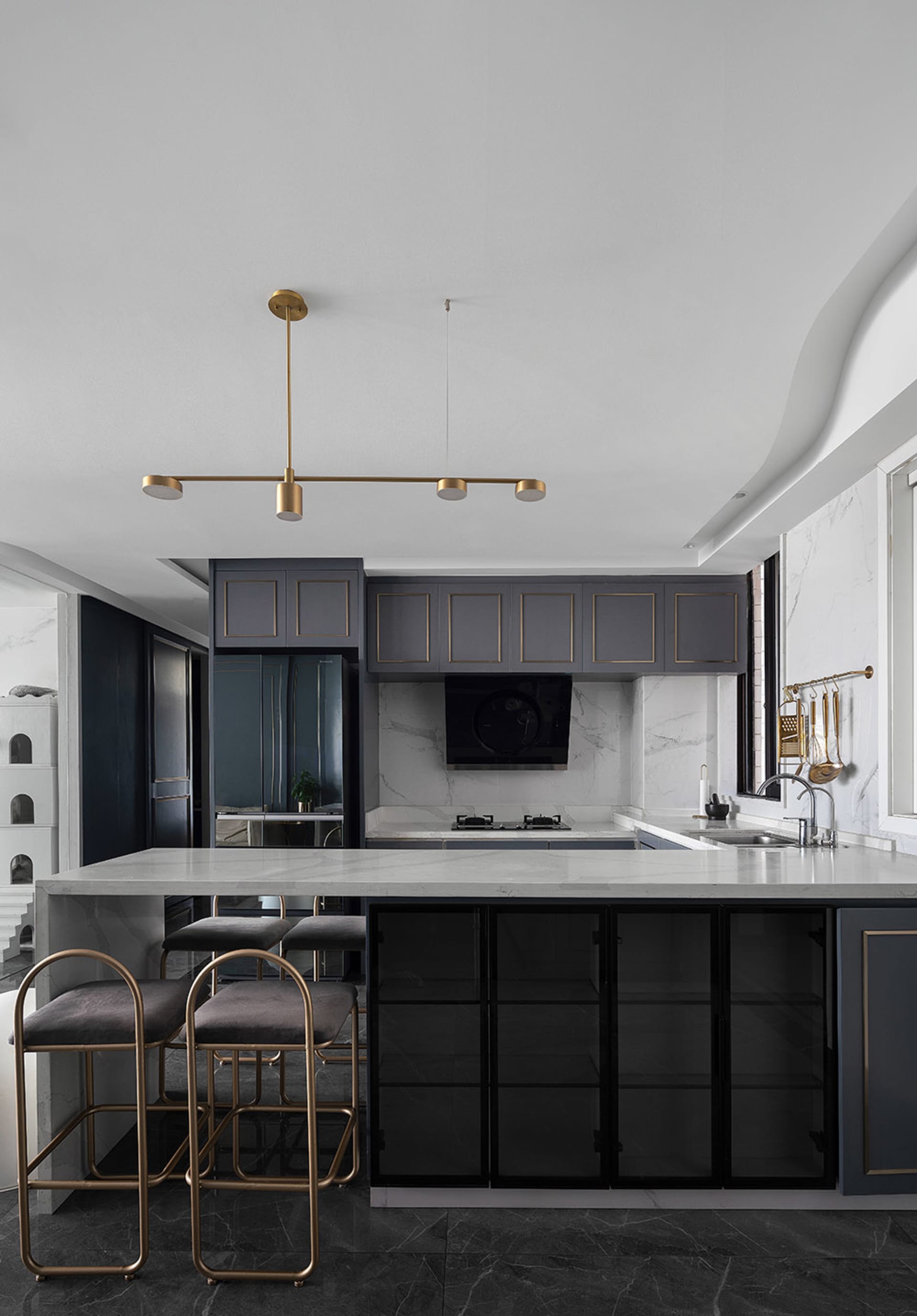 A modern kitchen featuring marble countertops and decorative lighting fixtures.