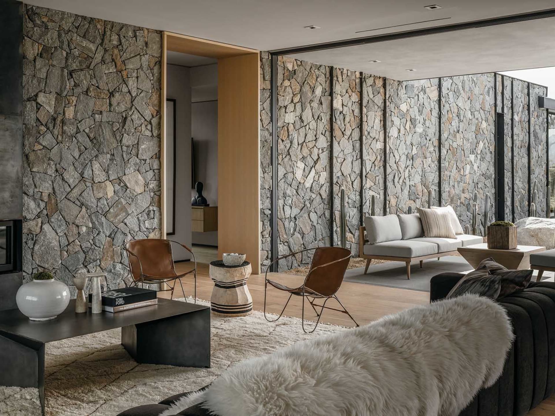 A modern living room featuring stone walls and minimalist furniture with a cozy atmosphere.