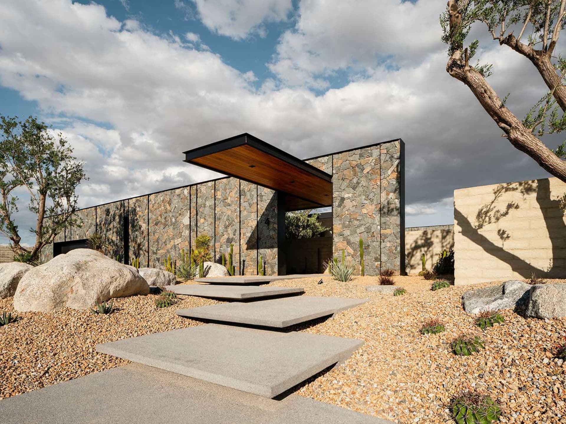 Modern residential exterior featuring stone cladding and concrete materials.