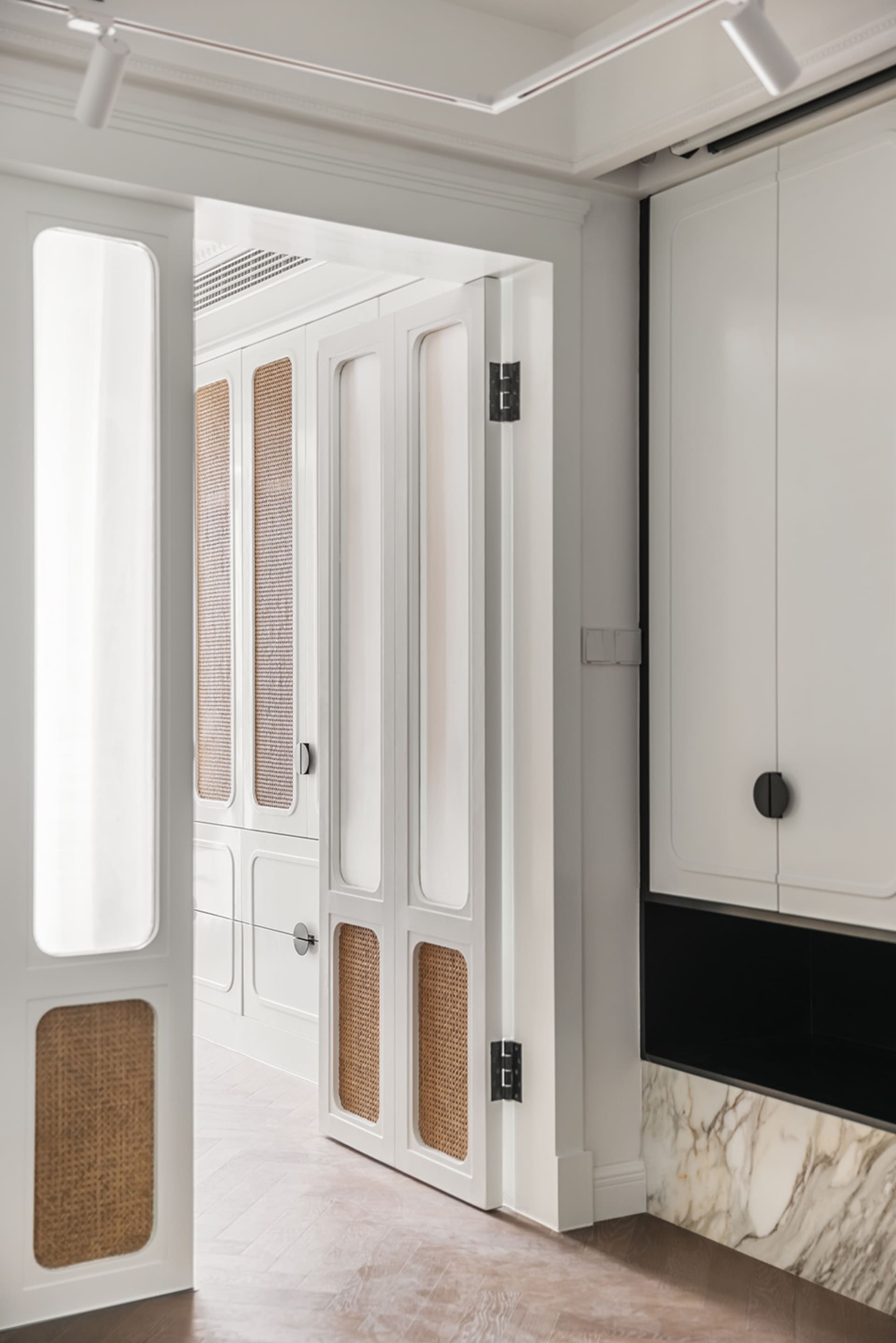 Interior shot of a modern closet with white painted walls, natural woven accents, and sliding doors.