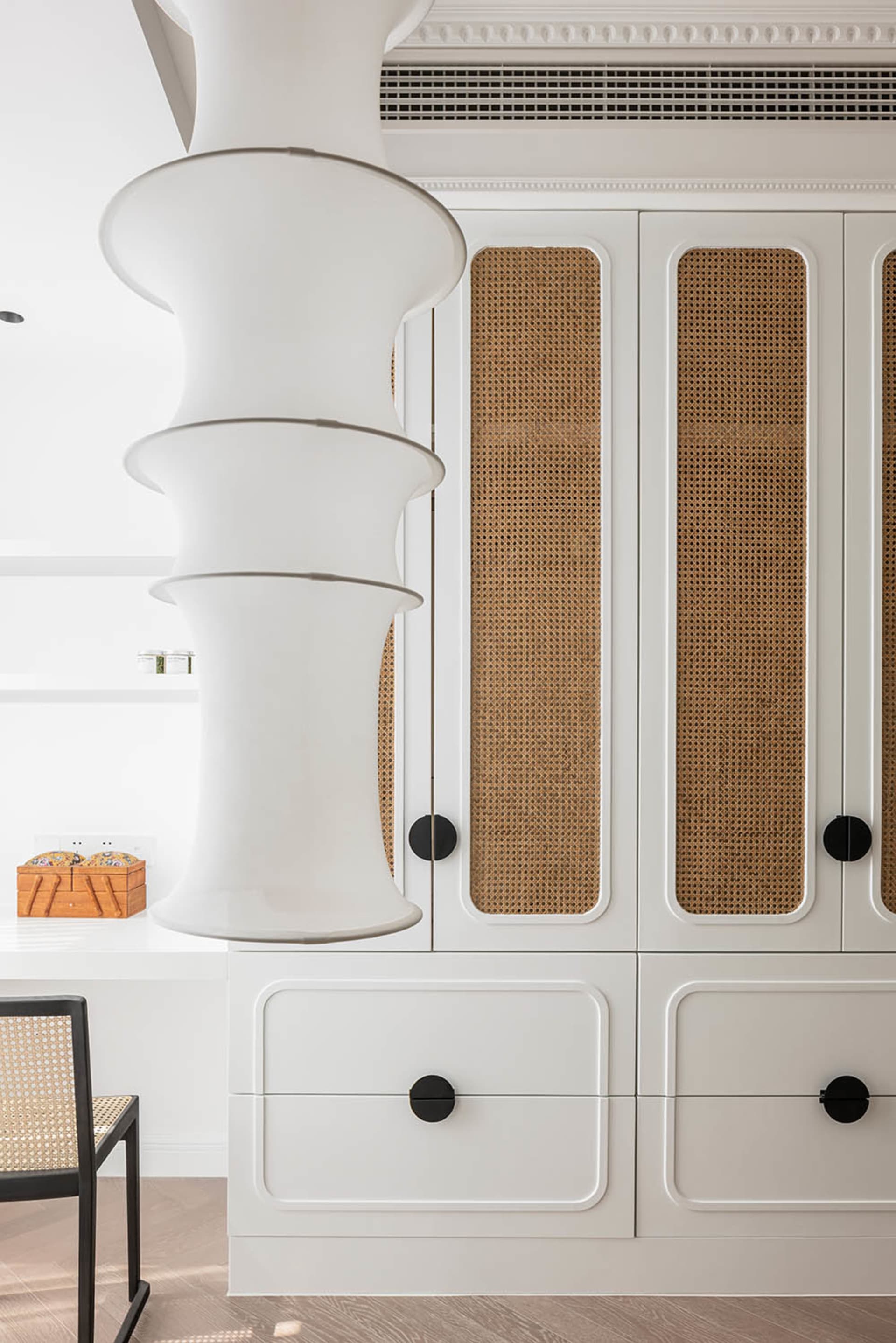 Modern white closet with rattan trim and black knobs.