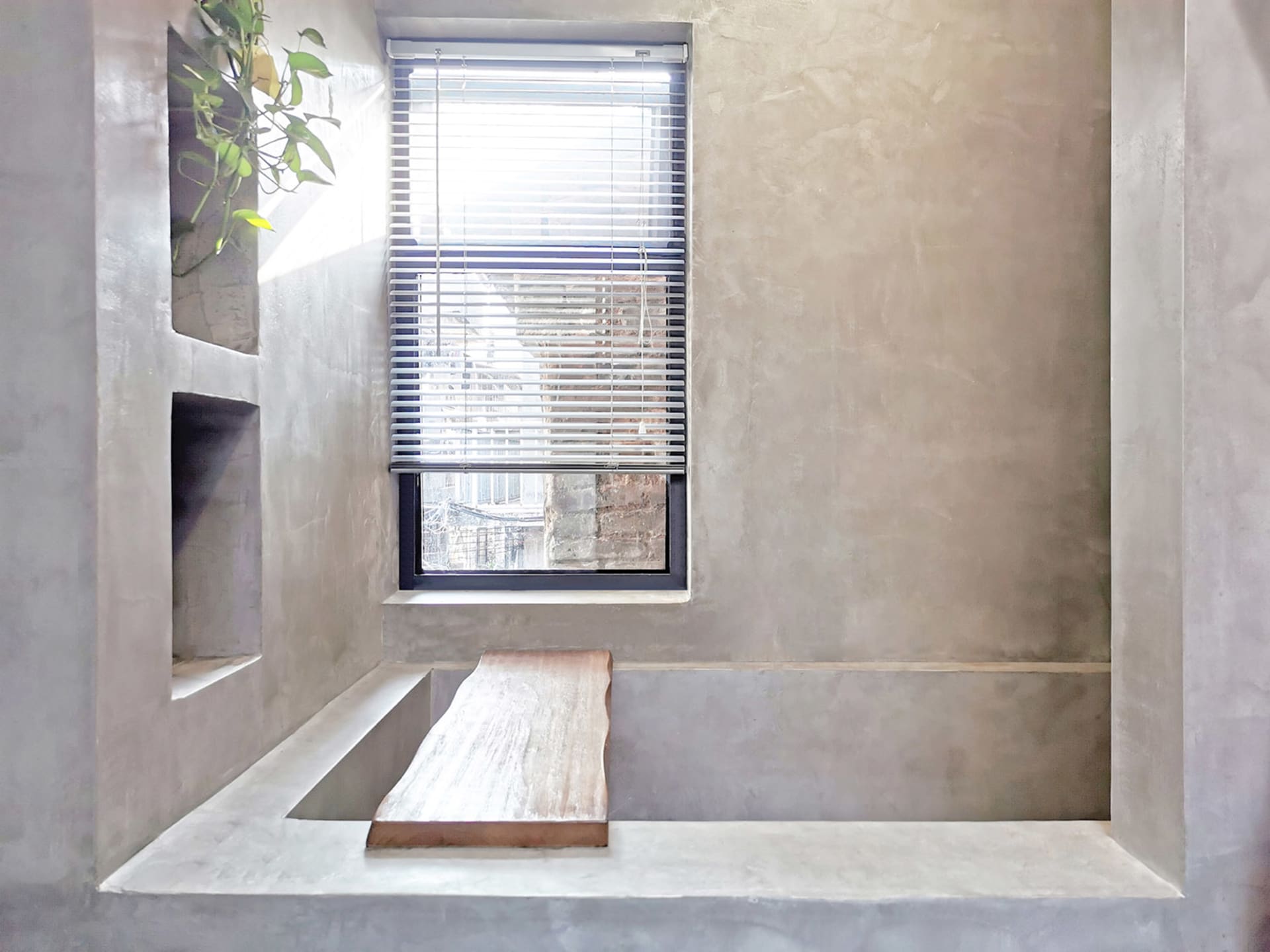Window with blinds in a modern minimalist bathroom made of concrete.