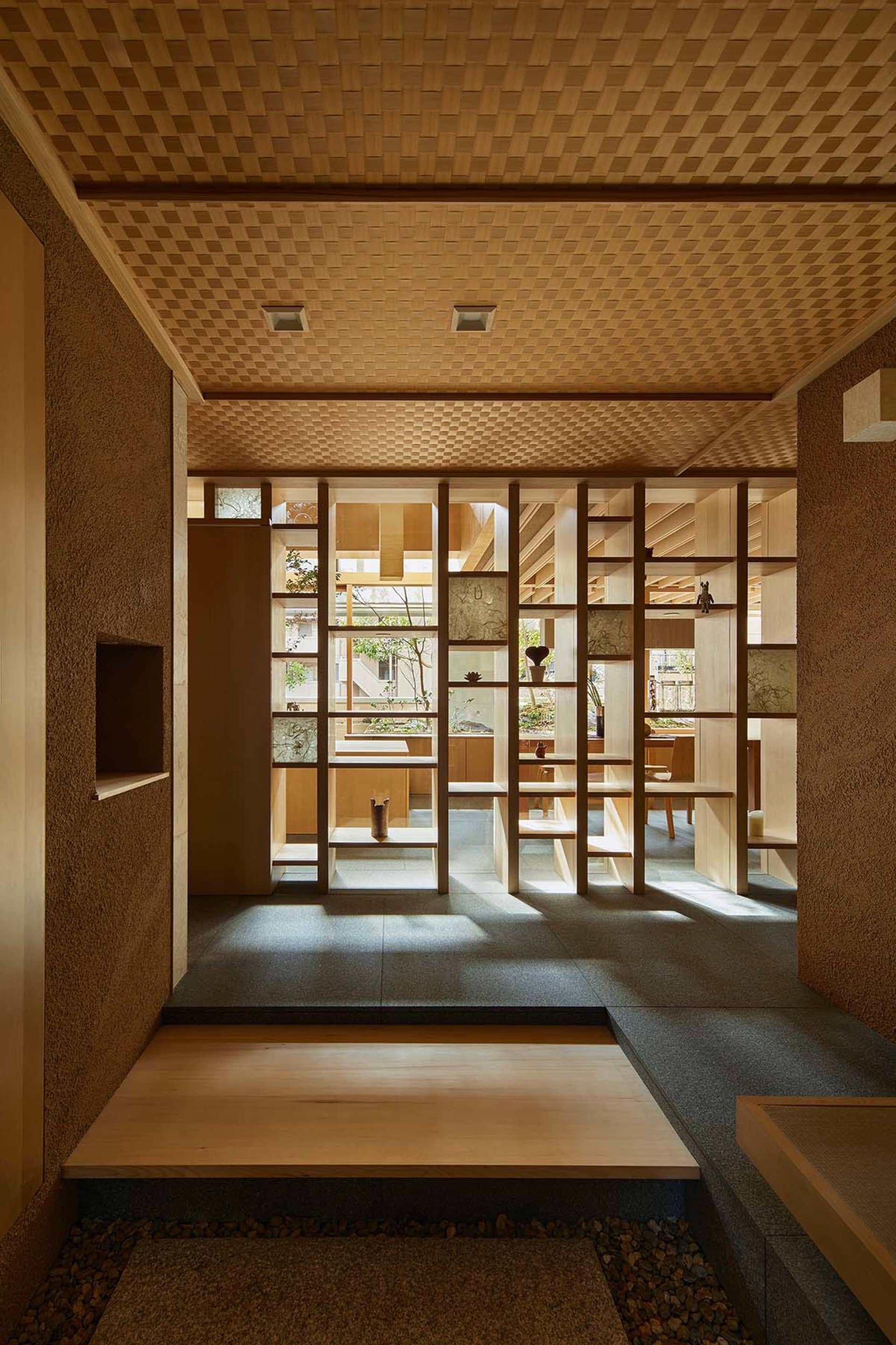 A minimalist interior featuring wooden elements and a sunlit space with shelves and decorations.