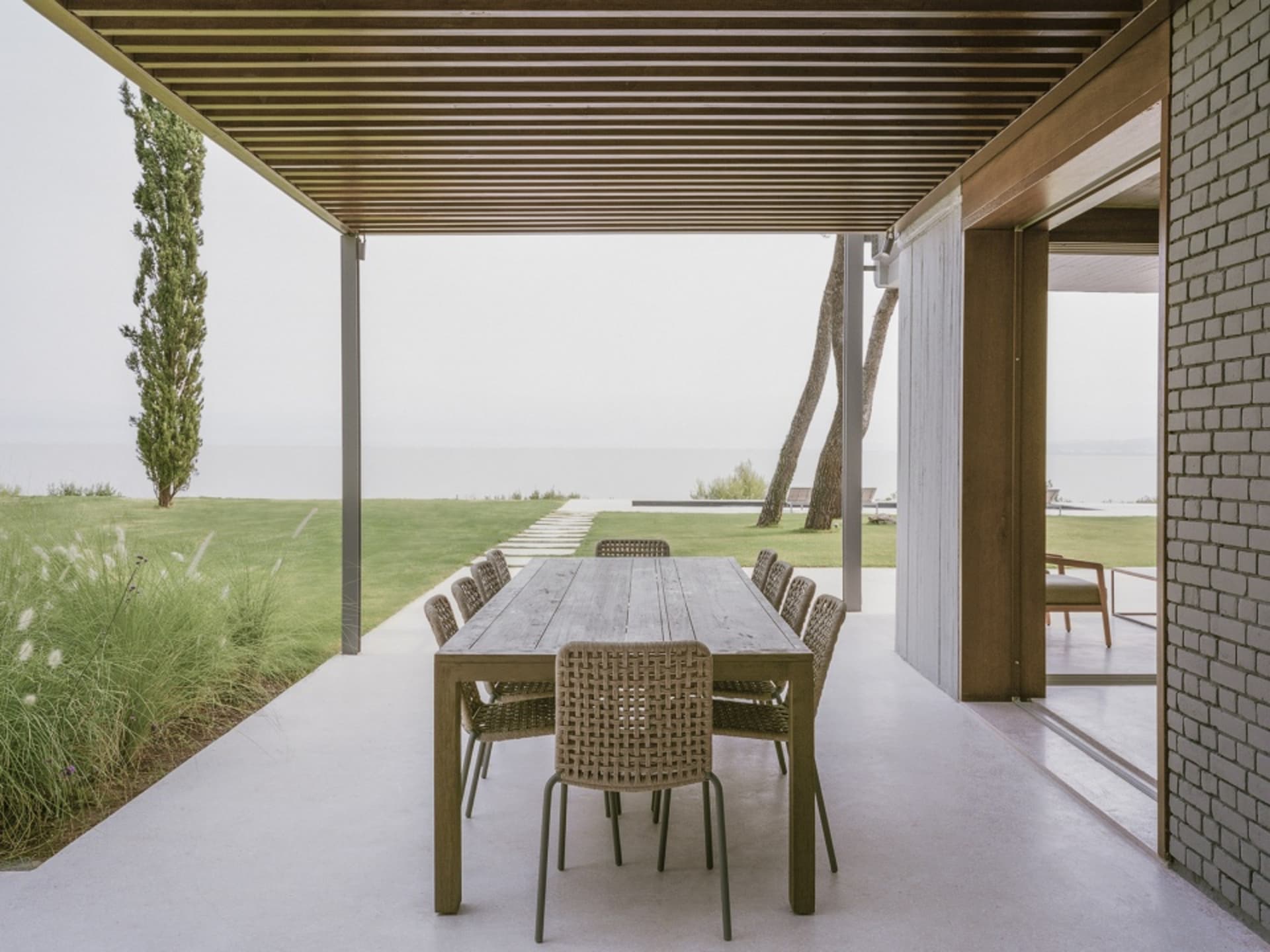 Outdoor dining area featuring a wooden table and rattan chairs with a sea view.