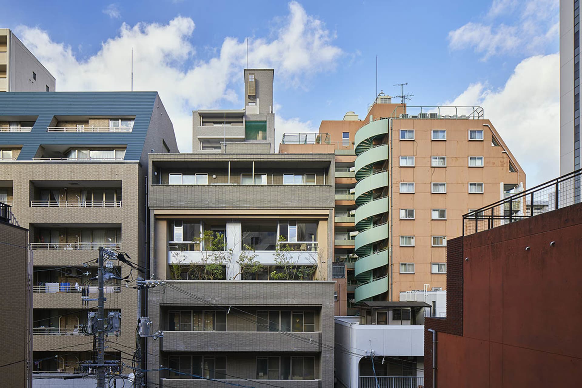 一座擁有磚塊與混凝土外牆的現代住宅建築,設有陽台與都市基礎設施。