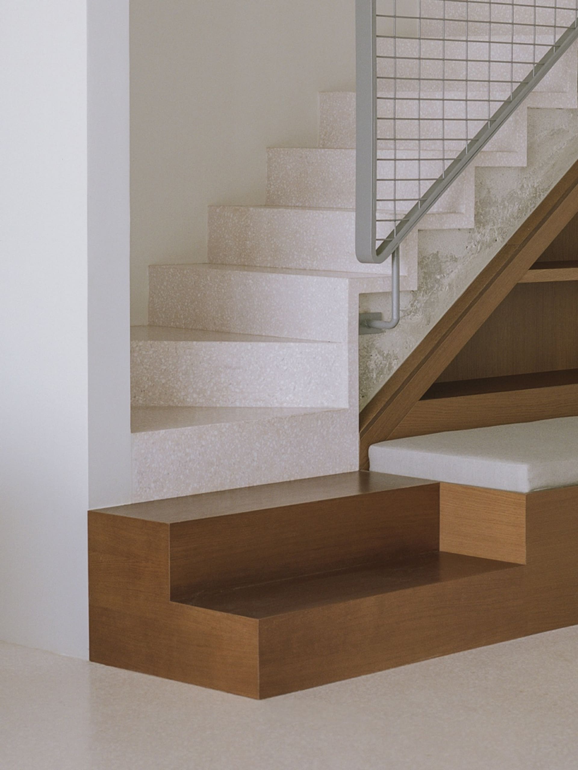 Modern concrete staircase with wooden steps and metal railings.