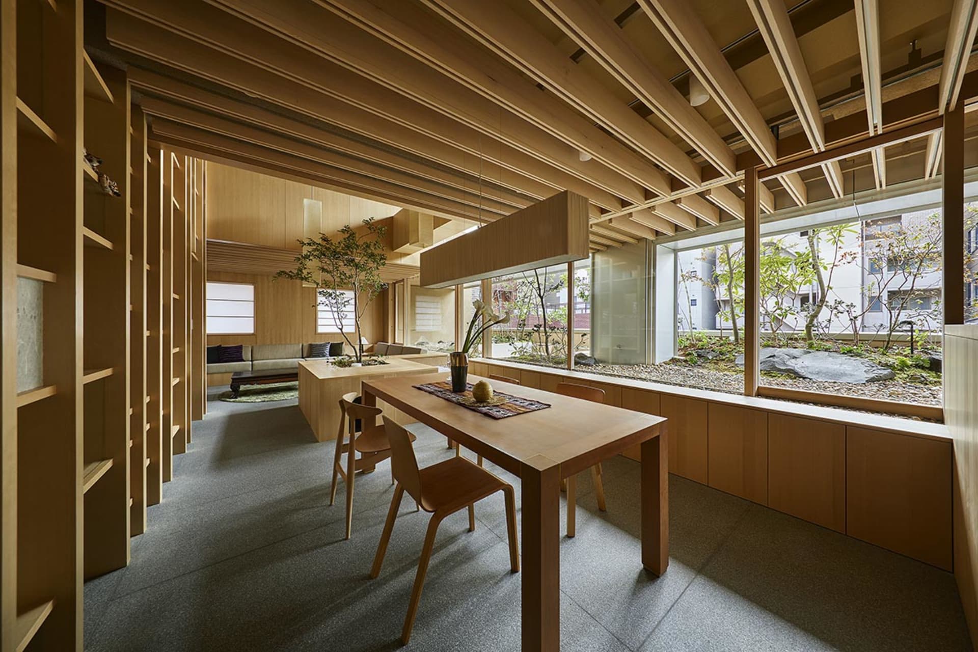 Modern interior design featuring a wooden table with a vase and fruits, surrounded by wooden shelves and a view of the courty