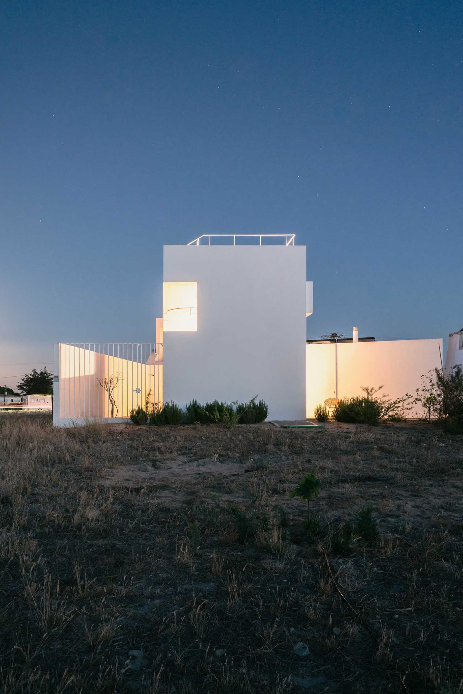 Modern minimalist white house at night with light on