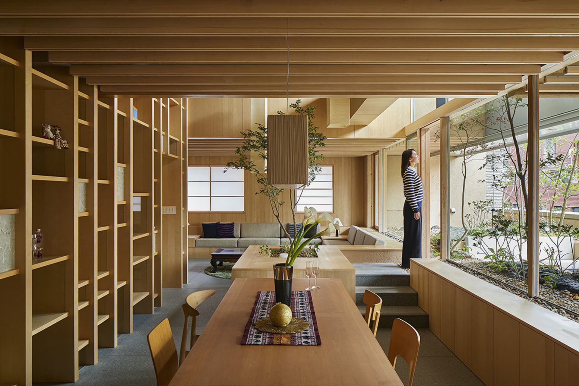 現代住宅空間,採用木質內裝,設有餐桌、書架,以及附沙發與咖啡桌的客廳區域