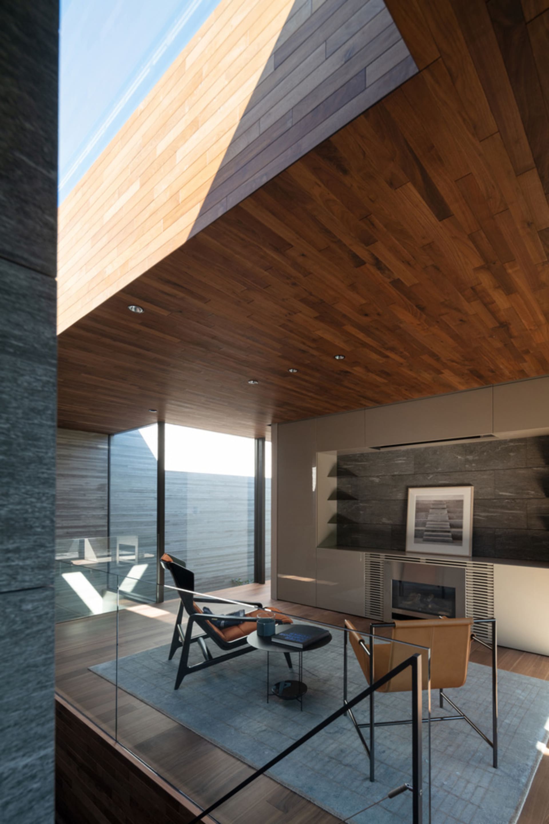 A modern living room with a wooden ceiling and floor, featuring contemporary furniture and a fireplace.