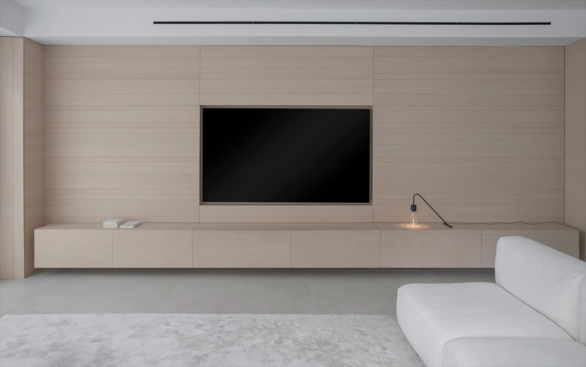 Modern living room featuring a floating wood entertainment unit with a flat-screen TV and minimalistic decor.