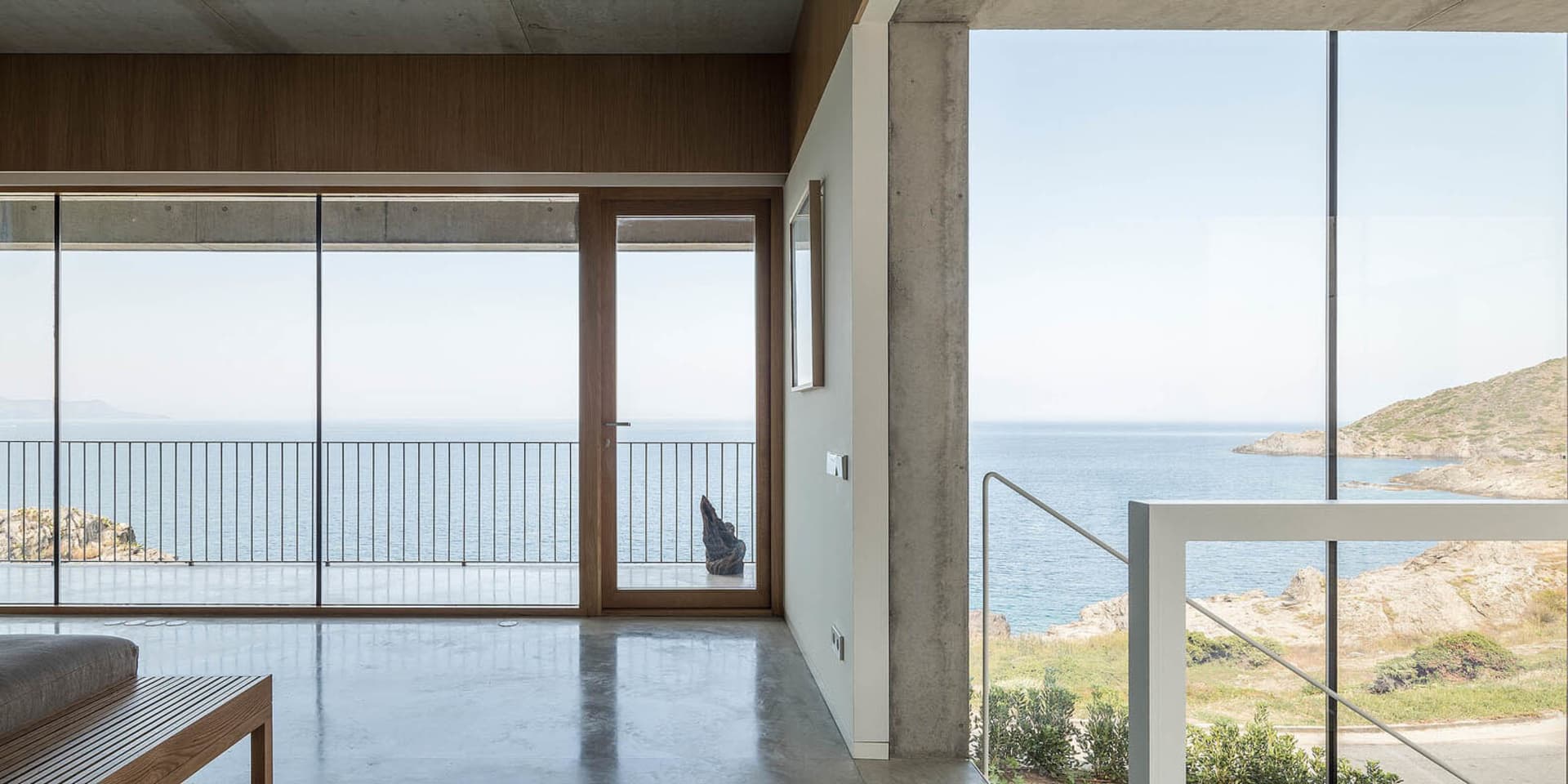 Interior view of a modern, minimalist residential space featuring concrete and glass materials.