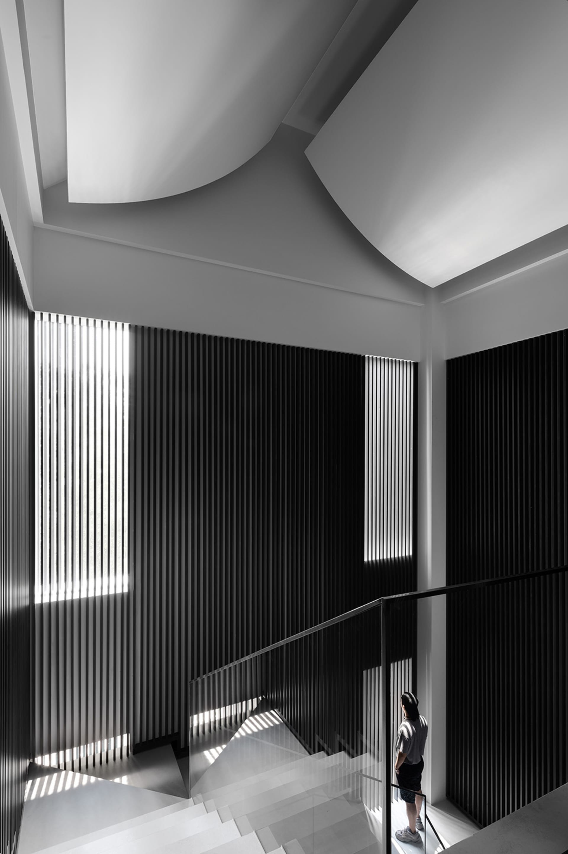 A minimalist staircase with glass railings and a geometric design.