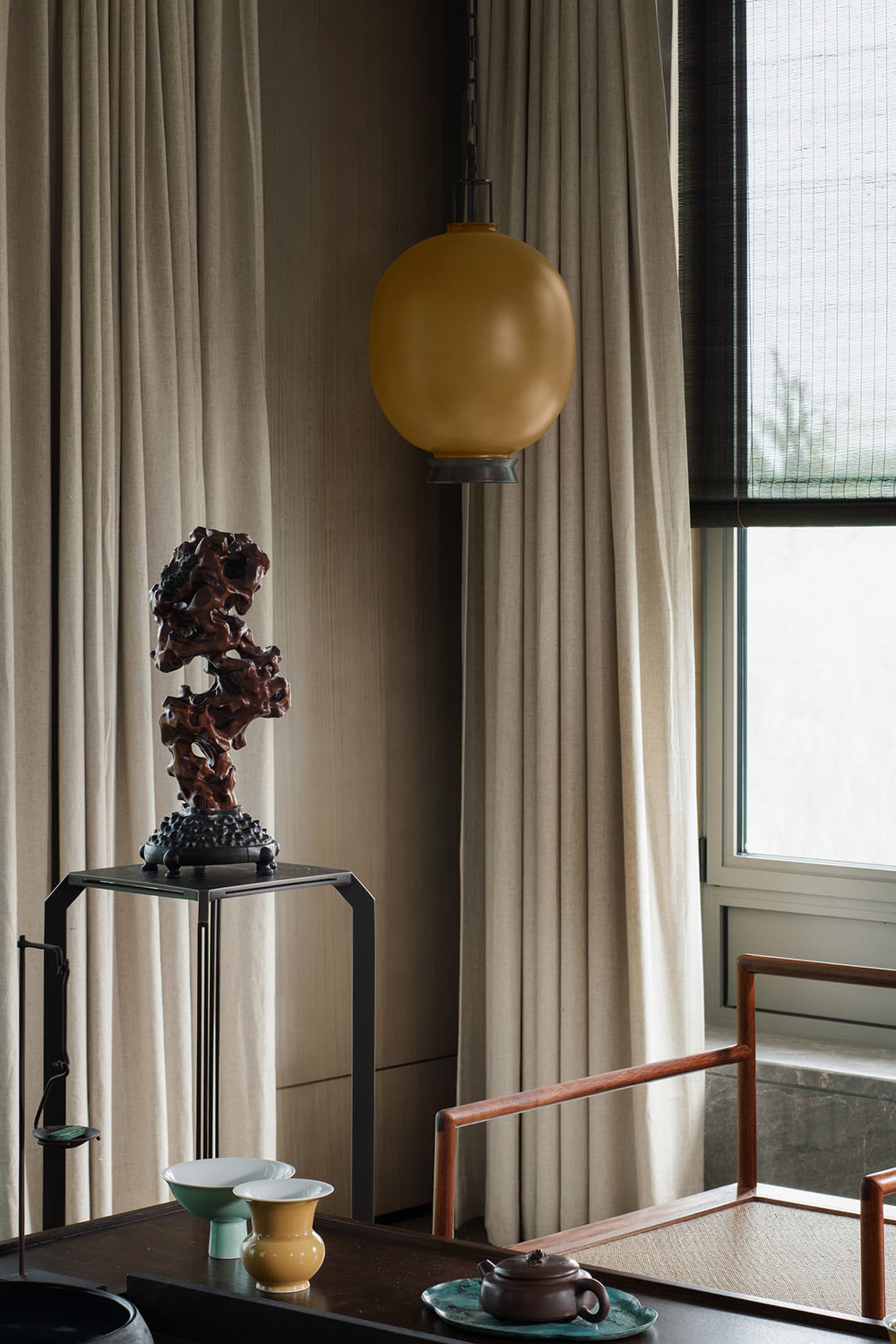 Modern minimalist living room with wood furniture, fabric curtains, and ceramic vases and teapot.