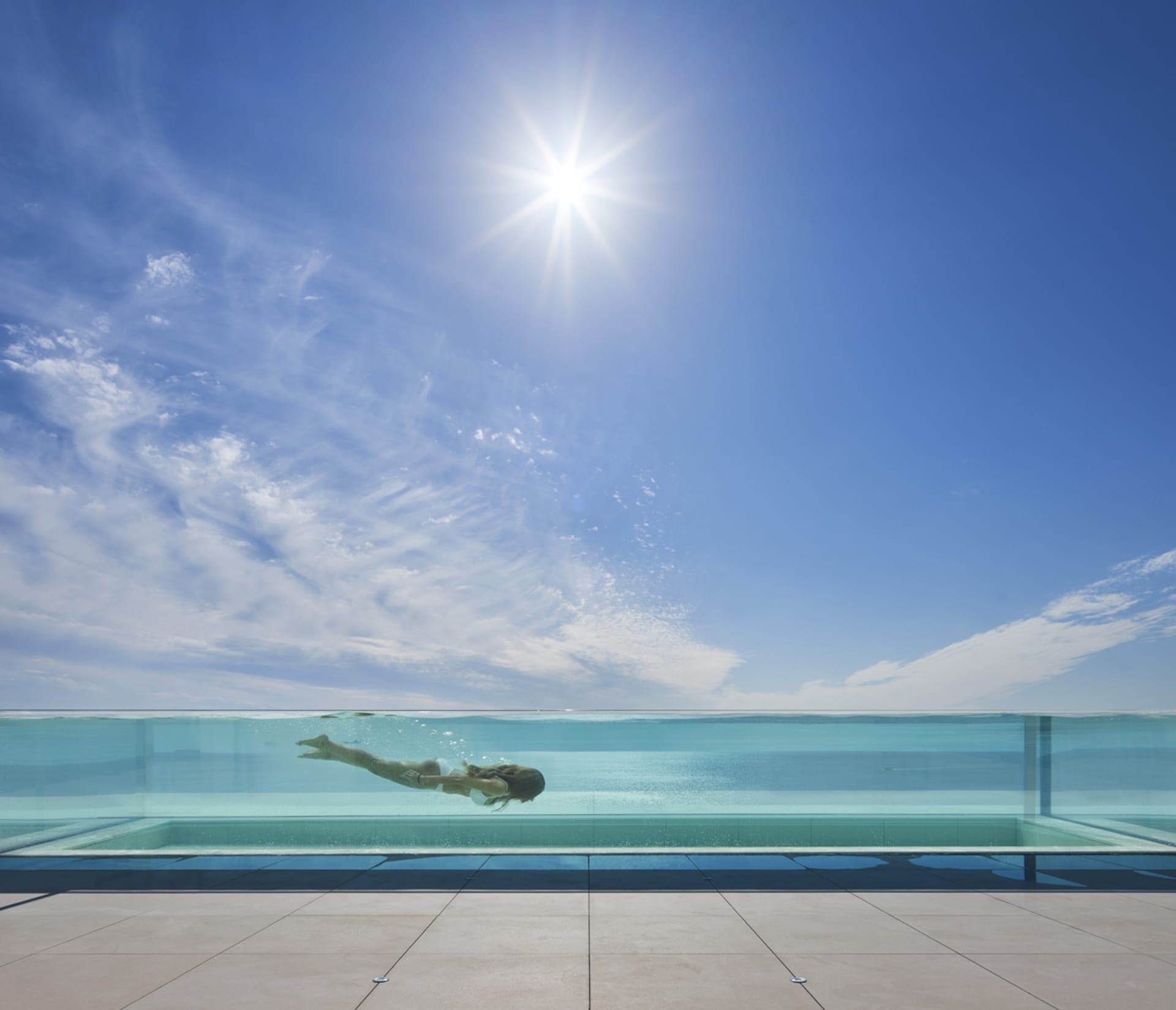 A modern swimming pool with a glass edge and clear blue water.