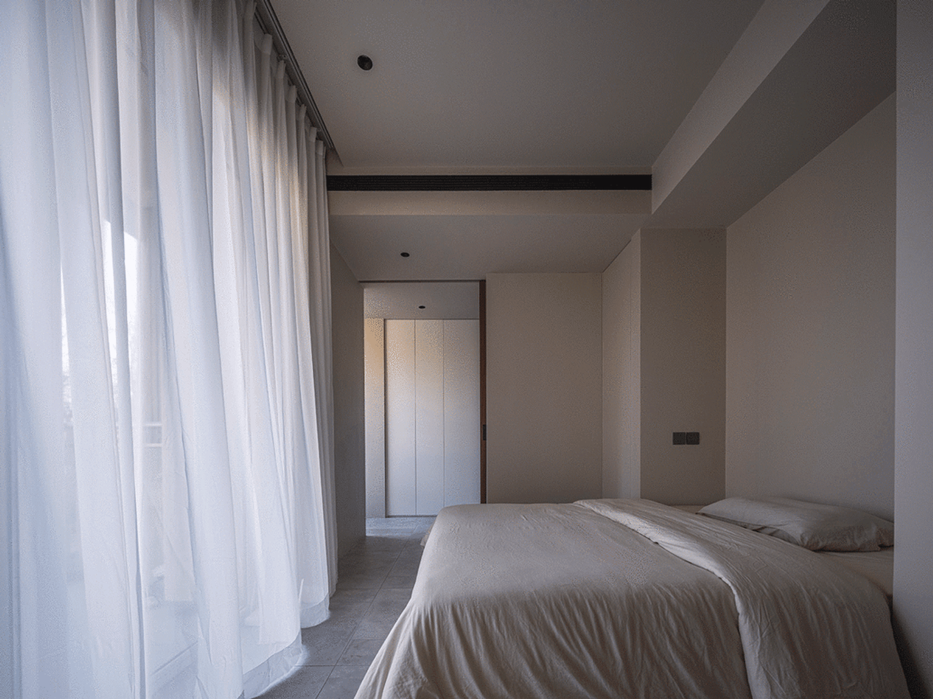 A minimalist bedroom featuring neutral colors.